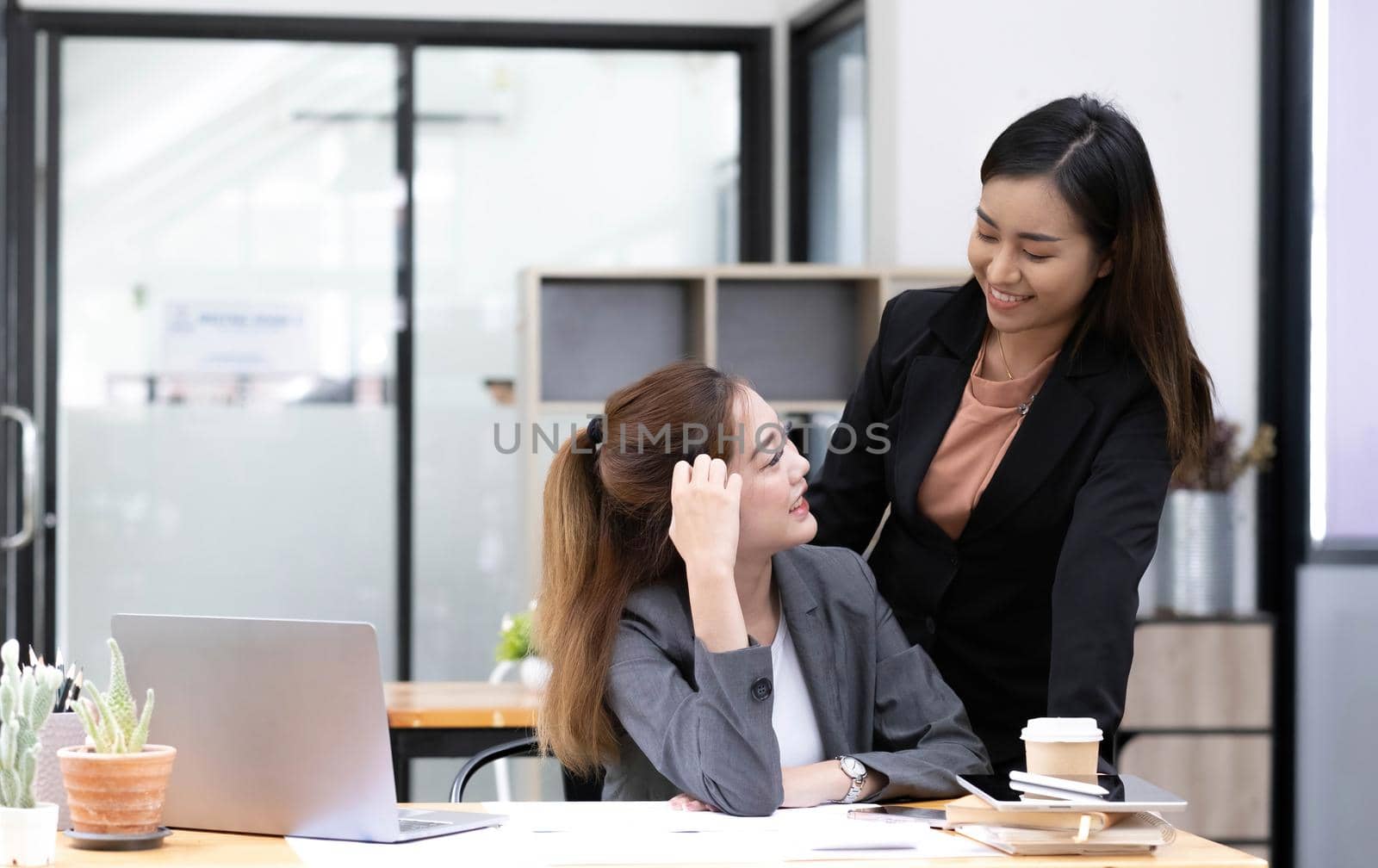 Asian business man present and explain work to female colleague, using laptop computer in office at night. Teamwork, coworker cooperation, financial marketing team, or corporate business concept..