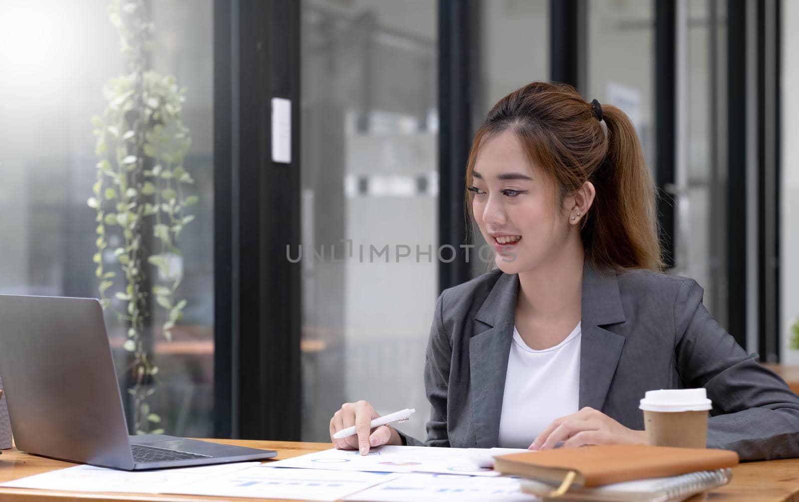 Beautiful Asian businesswoman work using a tablet and a laptop with documents placed at the office. by wichayada