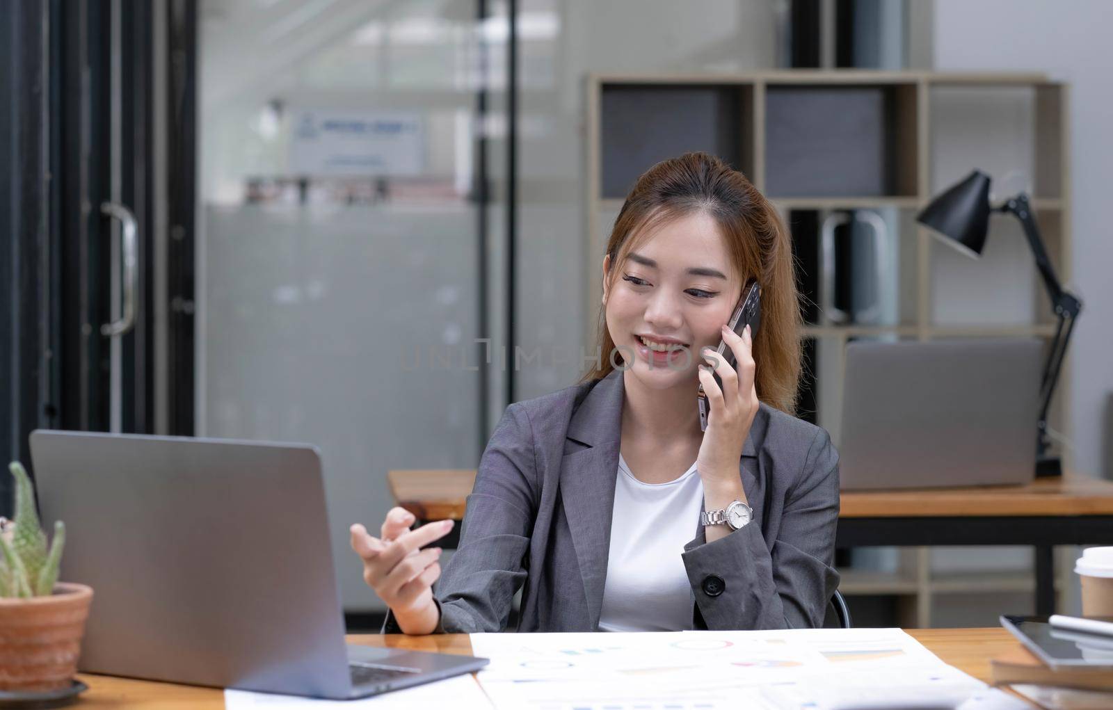 Asian business woman have the joy of talking on the phone, laptop and tablet on the office desk. by wichayada