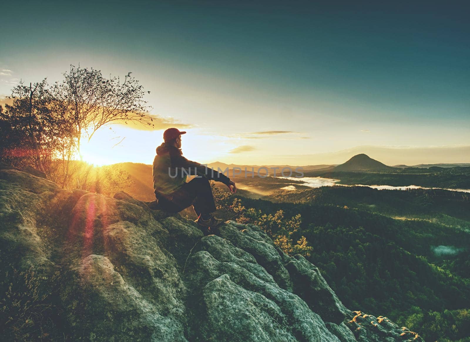 Man alone ath edge. Hiker enjoy view into fairy landscape. Sharp sun rays 