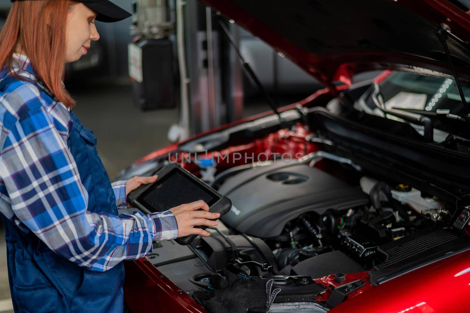 Caucasian female auto mechanic uses a special computer to diagnose faults