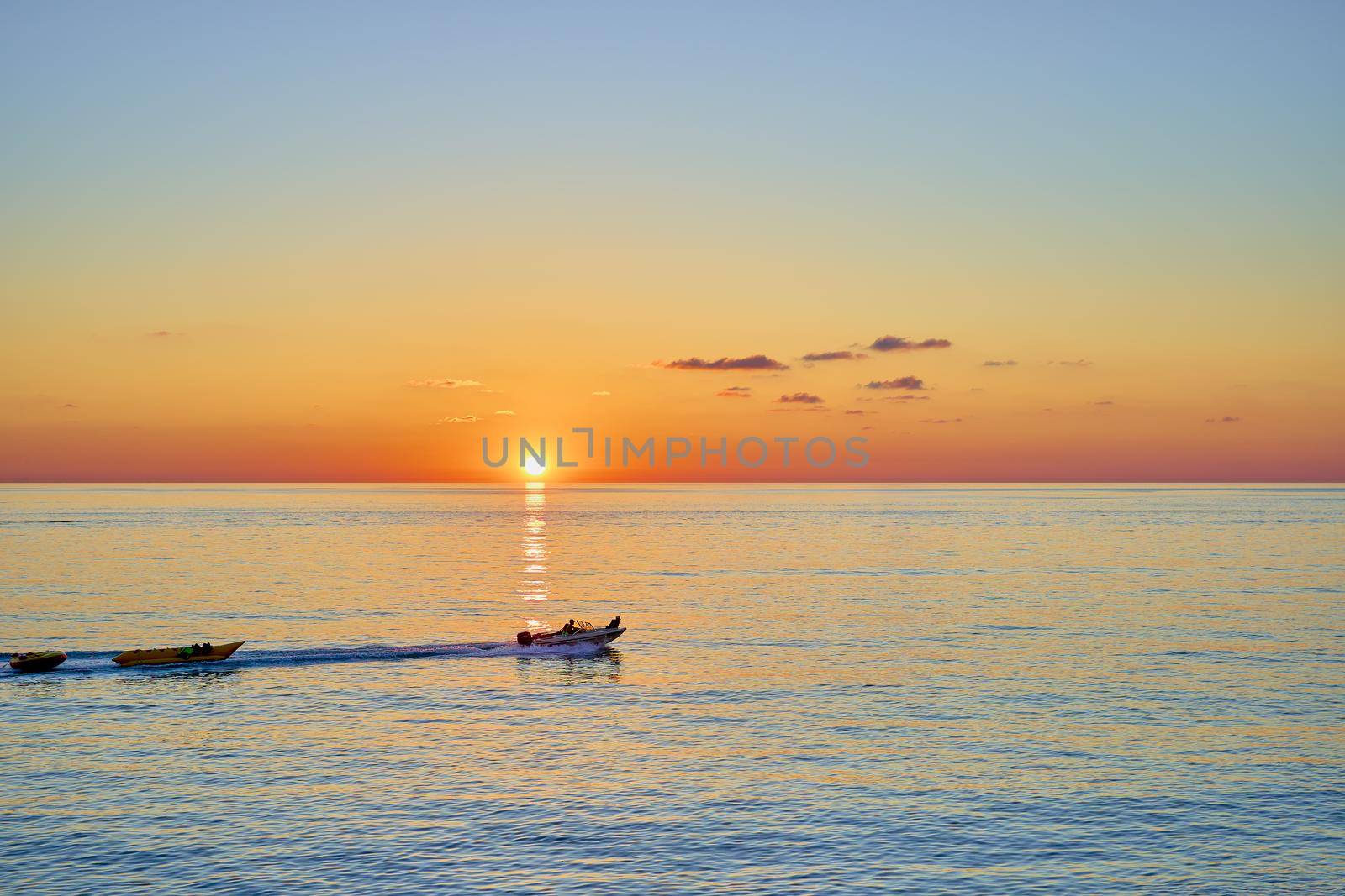 Sunset over the sea with a sailing boat in the distance. Beautiful seascape from the shore.