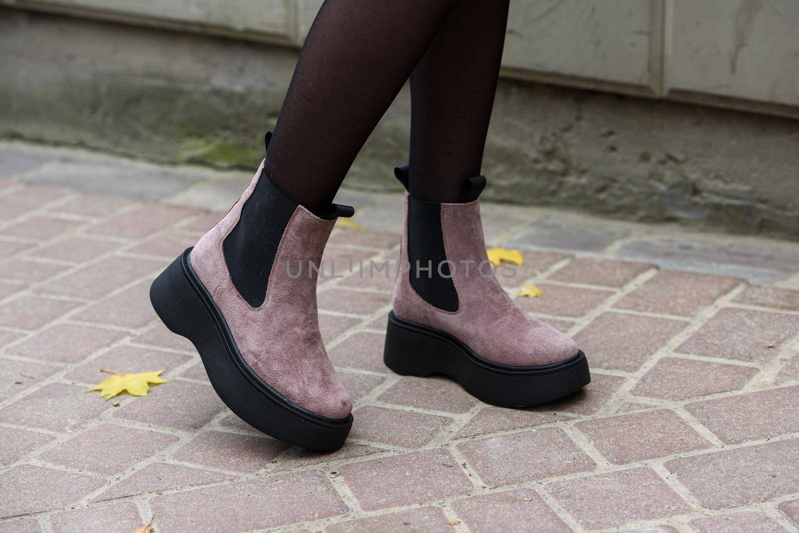 Women's autumn pink suede ankle boots. side view. Fashion shoes. Outdoors. stone pavement