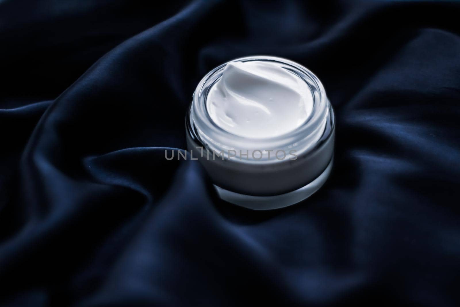 Beauty, anti-age cosmetics and skincare concept - Luxury face cream jar on a dark blue silk