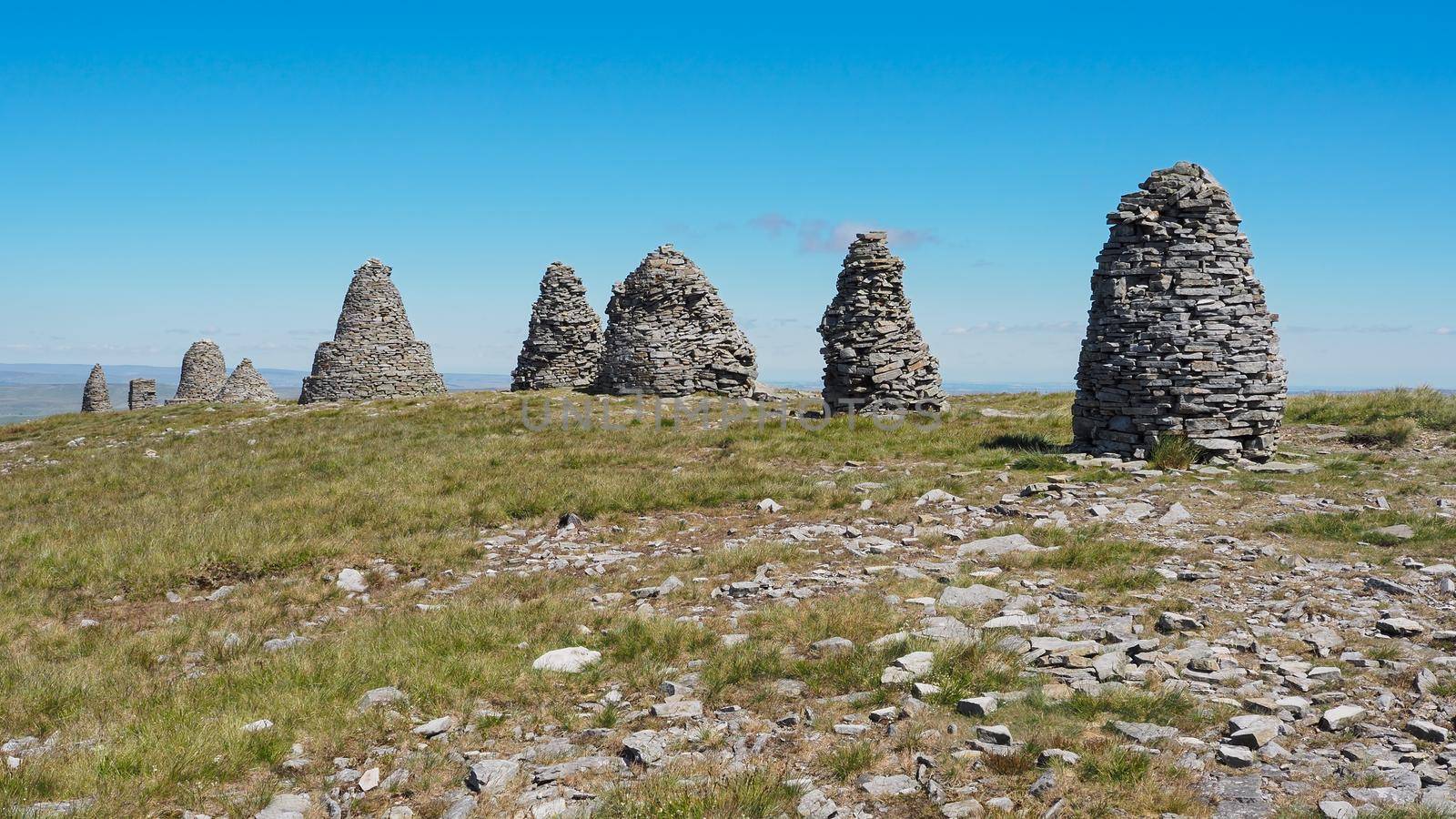 The stone cairns of Nine Standards Rigg under blue sky near to the summit of Hartley Fell, Eden Valley, North Pennines, Cumbria, UK