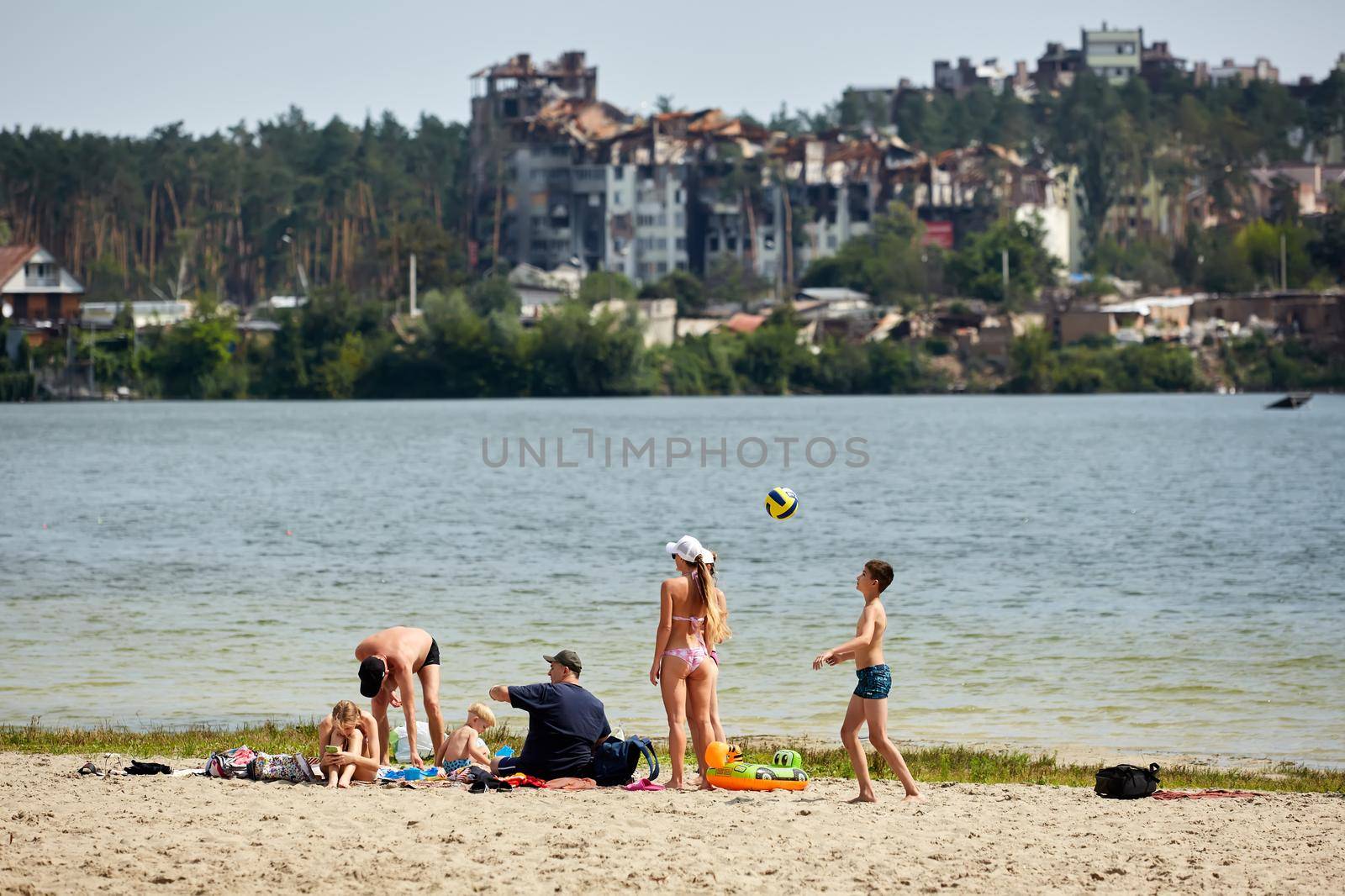 Irpin, Kyiv region, Ukraine - 25 August, 2022: Citi after the Russian occupation. People are having rest near lake opposite destroyed houses
