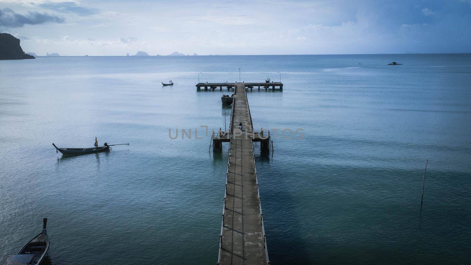 Aerial view from a drone of a pier in a tropical sea. A lot of Thai traditional longtail fishing boats in the sea.