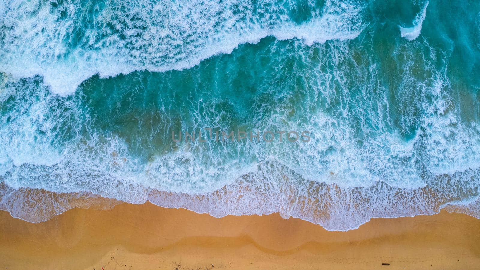 Beautiful sea waves and white sand beach in the tropical island. Soft waves of blue ocean on sandy beach background from top view from drones. Concept of relaxation and travel on vacation.