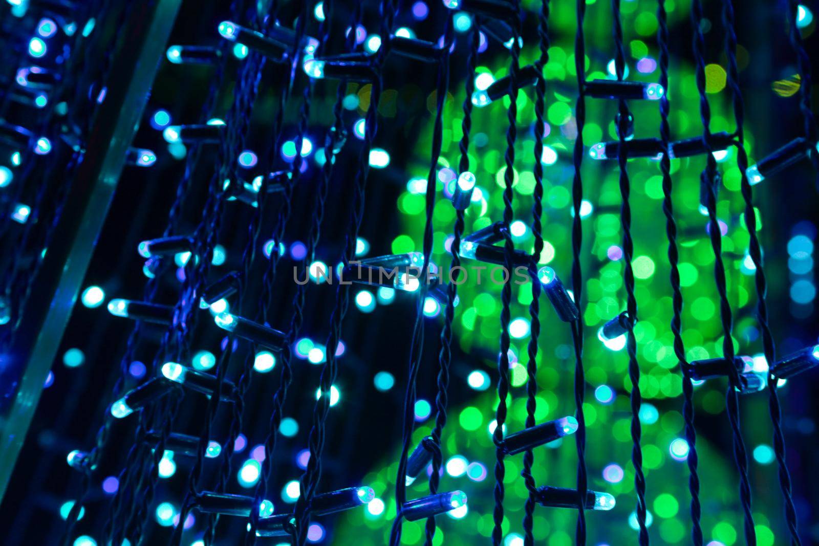 Blue garlands on a background of green festive illumination. Beautiful bokeh from many garlands at night.