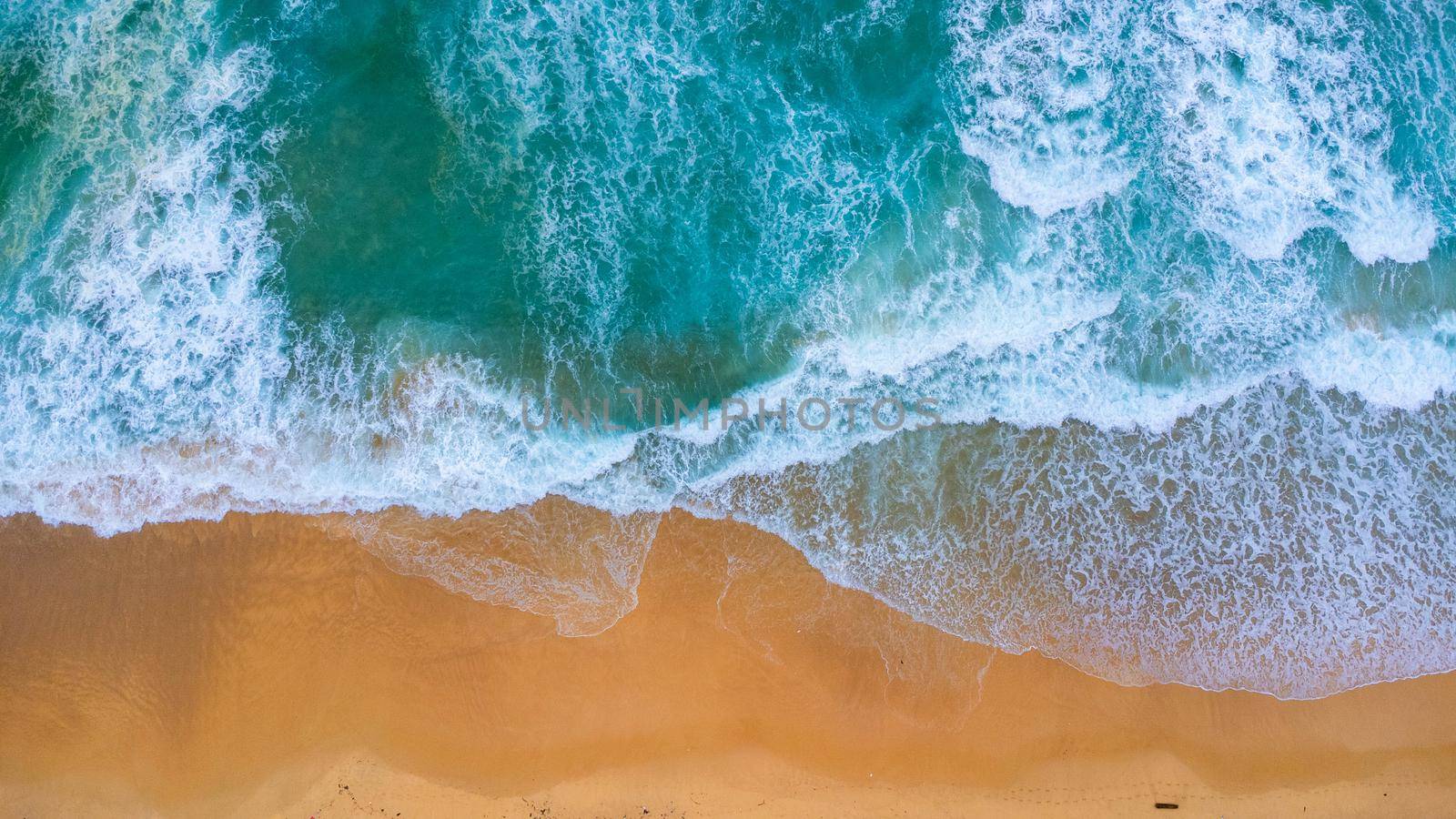 Beautiful sea waves and white sand beach in the tropical island. Soft waves of blue ocean on sandy beach background from top view from drones. Concept of relaxation and travel on vacation. by TEERASAK