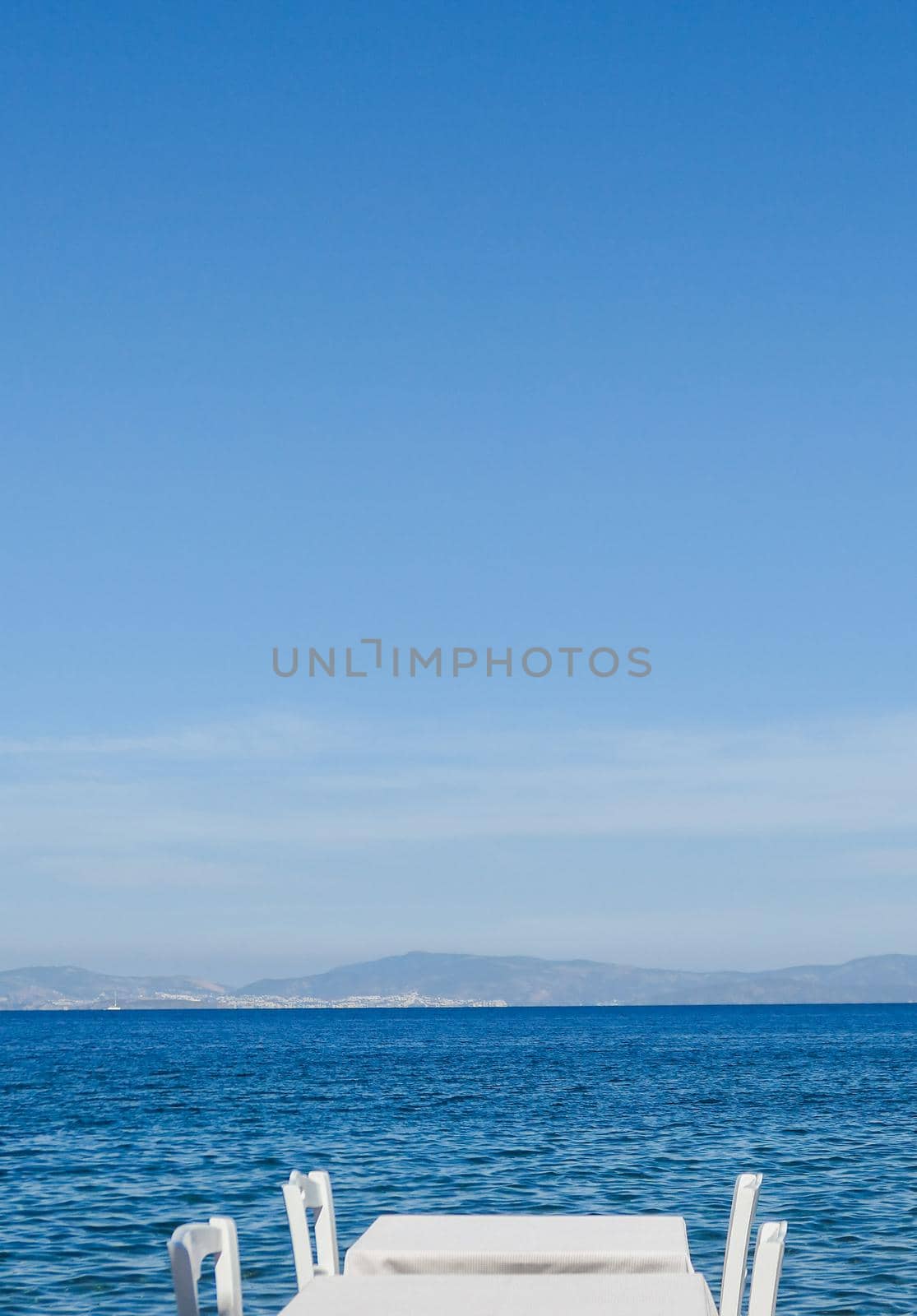 White restaurant tables on the beach in summer - travel, vacation and summer concept. The perfect lunch with a sea view