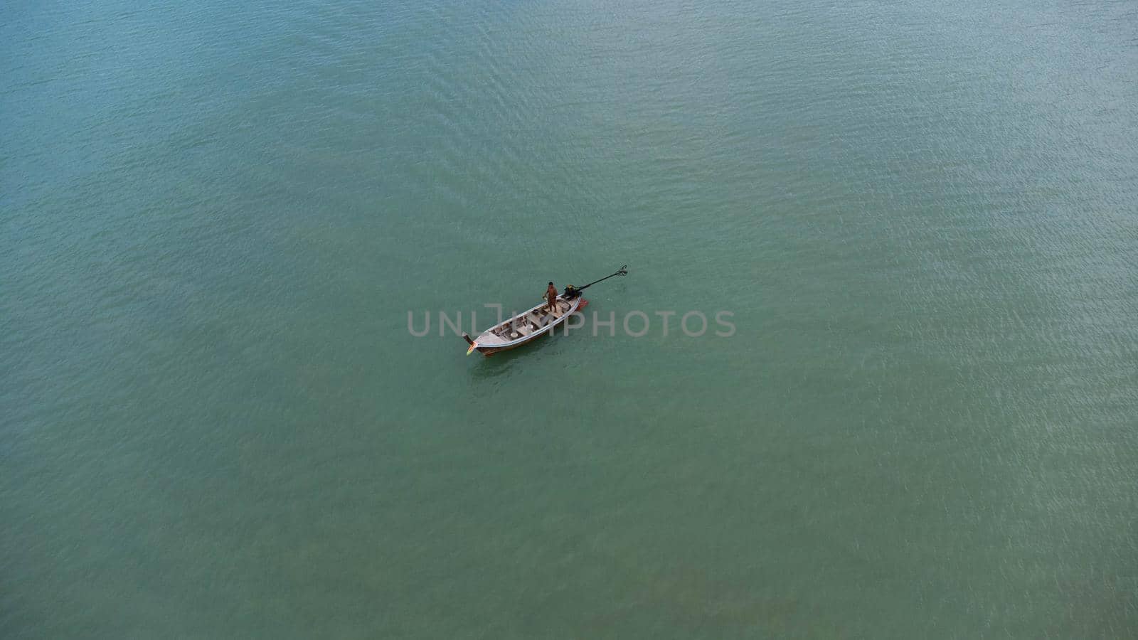 Aerial view from a drone of Thai traditional longtail fishing boats sailing in the sea. Top view of a fishing boat in the ocean. by TEERASAK