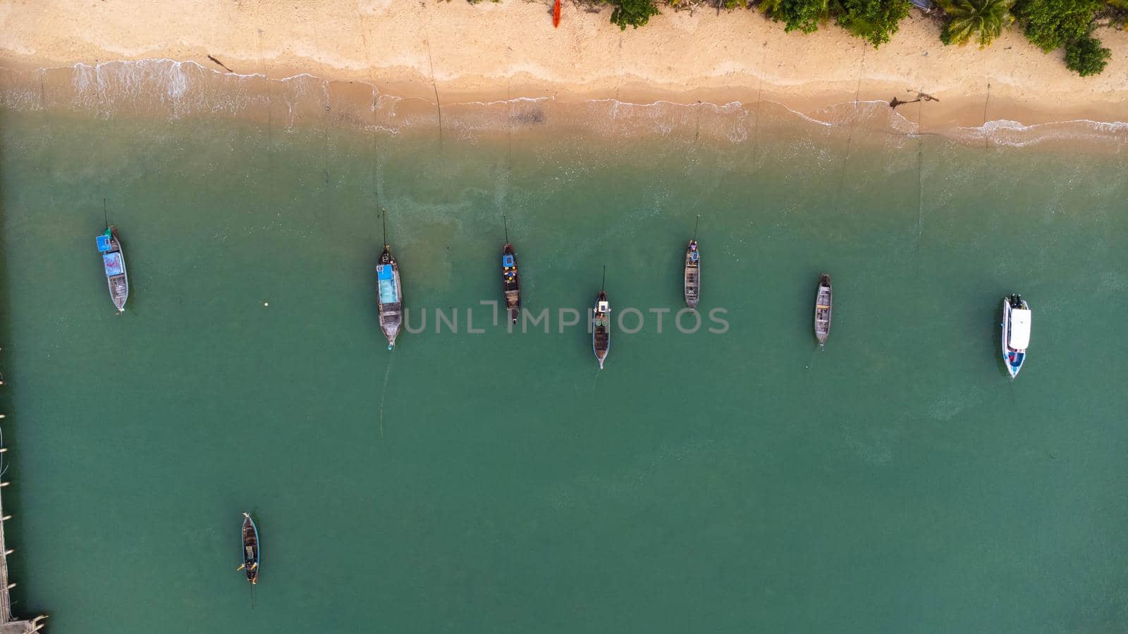 Many fishing boats near the seashore in tropical islands. Pier of the villagers on the southern island of Thailand. top view from drones. by TEERASAK