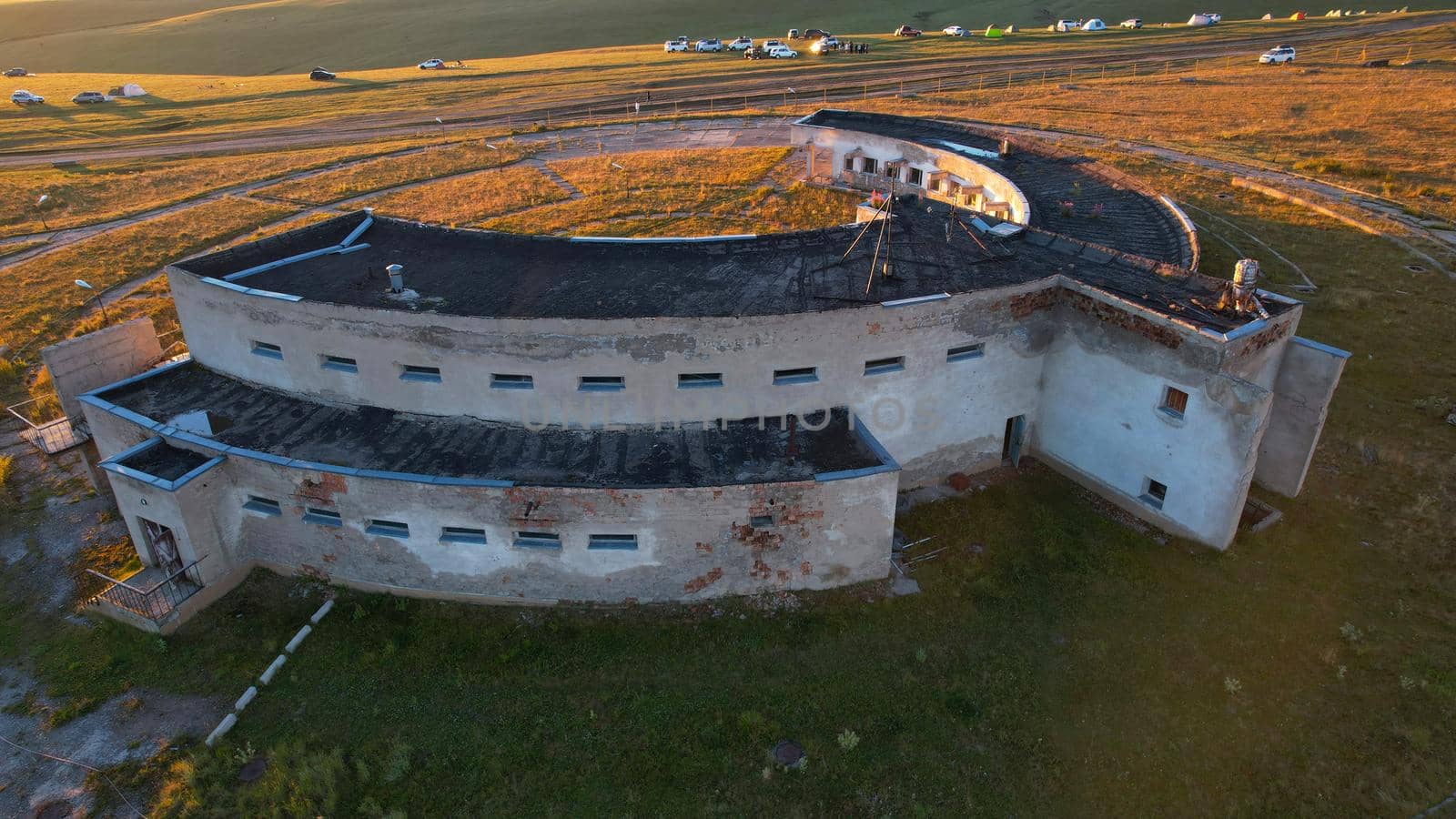 Bright dawn over the Assy-Turgen Observatory in the mountains. Aerial view from the drone of the camp of tents, cars and waking tourists. There is an old abandoned building. Kazakhstan, Almaty