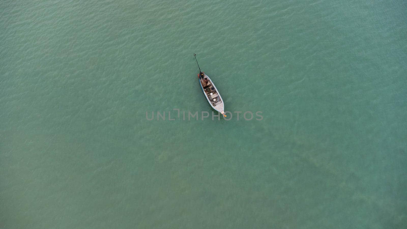 Aerial view from a drone of Thai traditional longtail fishing boats sailing in the sea. Top view of a fishing boat in the ocean. by TEERASAK