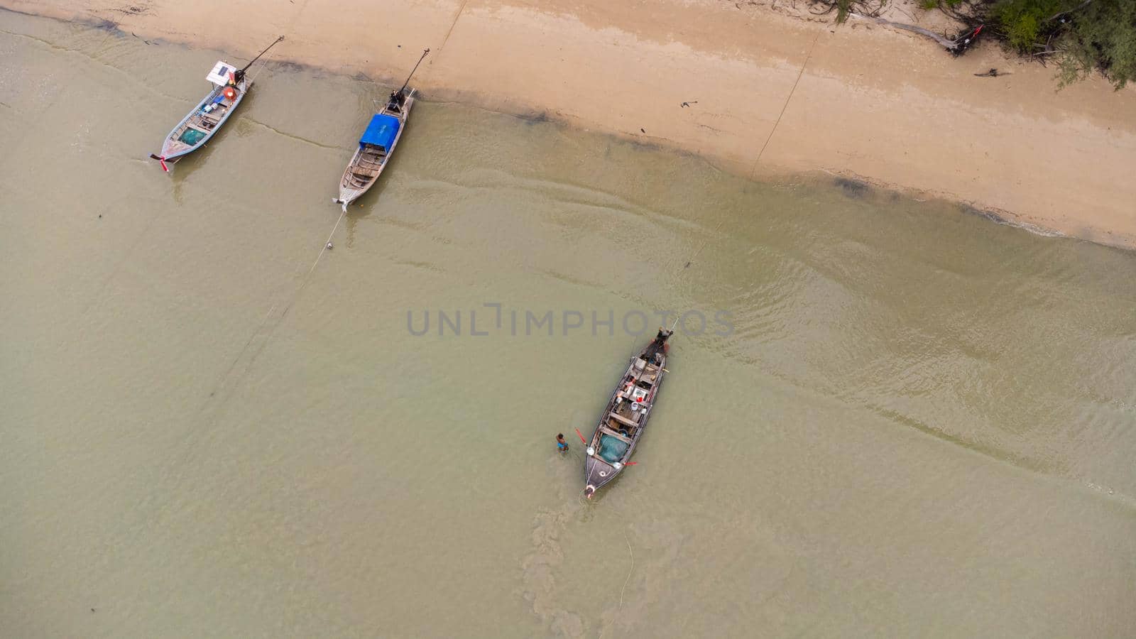 Aerial view from a drone of Thai traditional longtail fishing boats sailing in the sea. Top view of a fishing boat in the ocean.