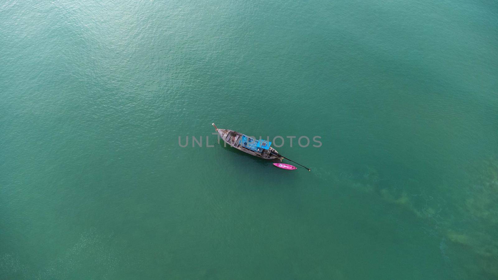 Aerial view from a drone of Thai traditional longtail fishing boats sailing in the sea. Top view of a fishing boat in the ocean.