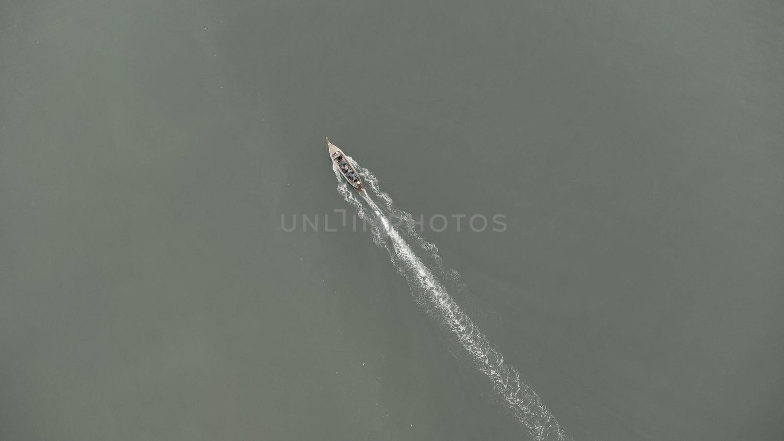 Aerial view from a drone of Thai traditional longtail fishing boats sailing in the sea. Top view of a fast moving fishing boat in the ocean. by TEERASAK