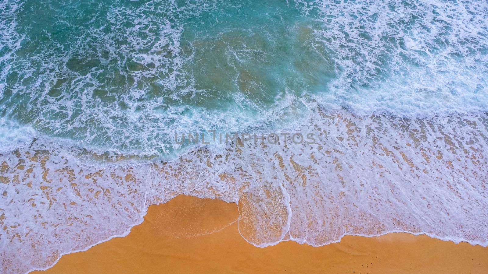 Beautiful sea waves and white sand beach in the tropical island. Soft waves of blue ocean on sandy beach background from top view from drones. Concept of relaxation and travel on vacation.