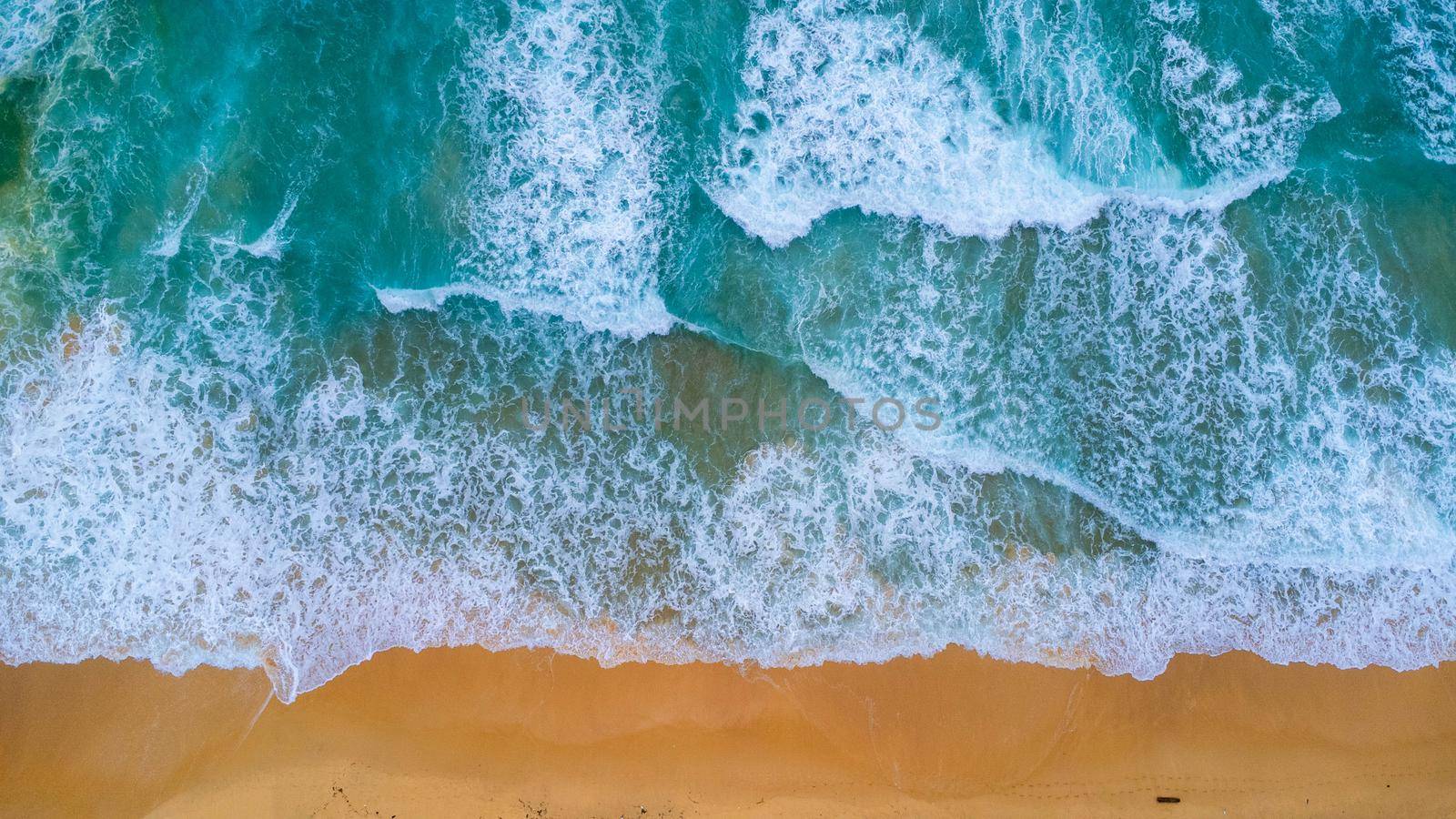 Beautiful sea waves and white sand beach in the tropical island. Soft waves of blue ocean on sandy beach background from top view from drones. Concept of relaxation and travel on vacation.