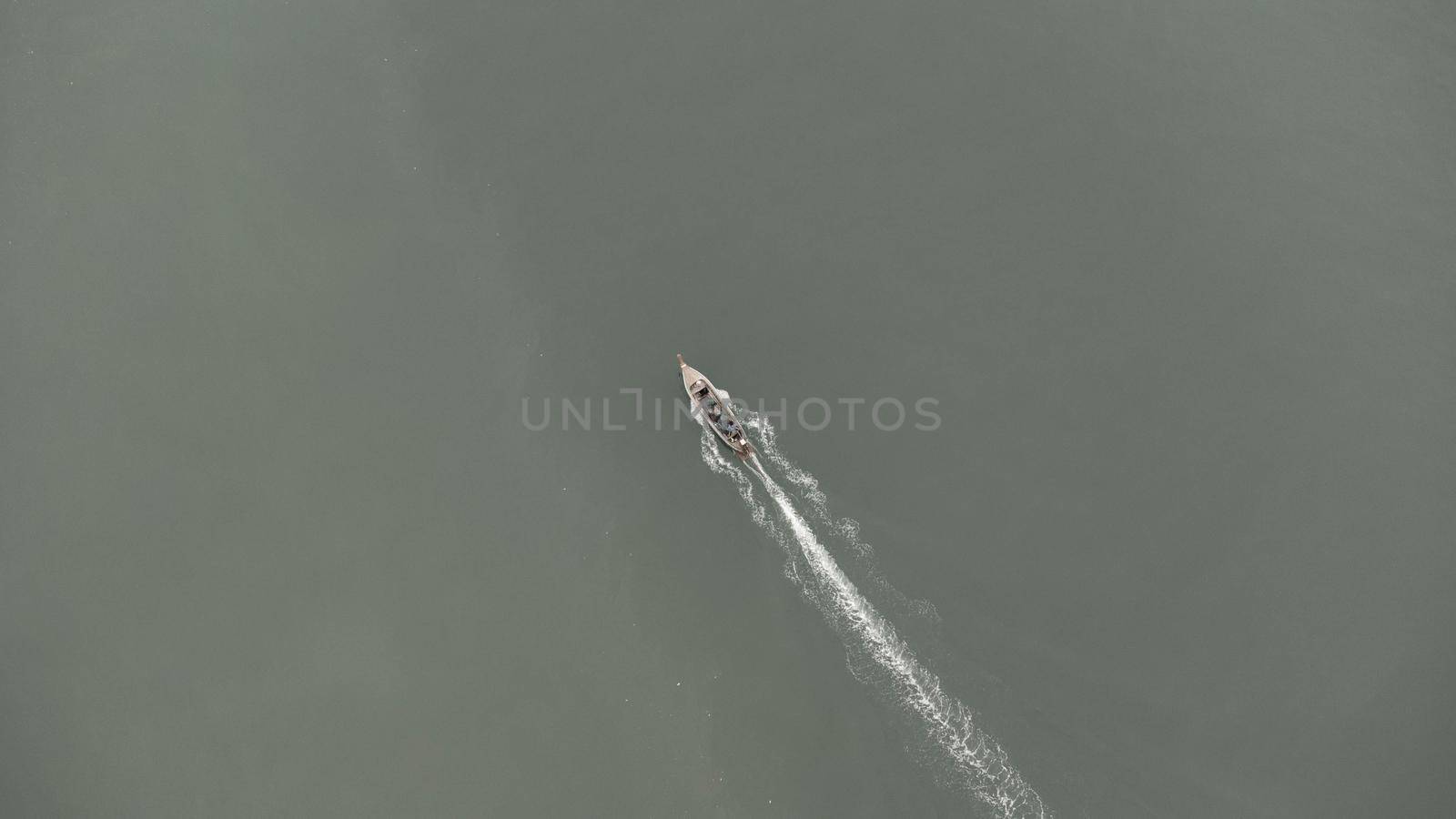 Aerial view from a drone of Thai traditional longtail fishing boats sailing in the sea. Top view of a fast moving fishing boat in the ocean.