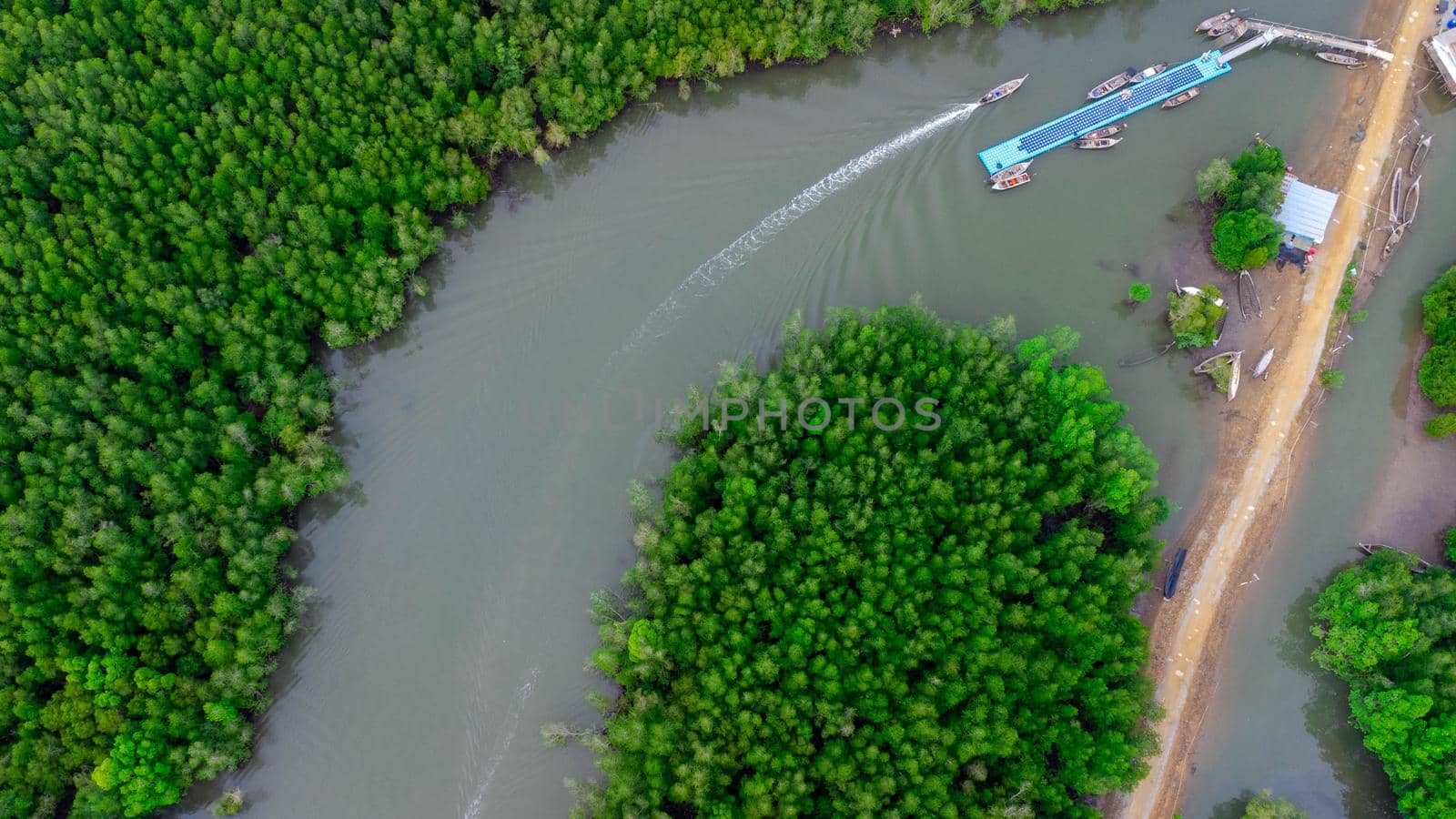 Aerial view of Thai traditional longtail fishing boats at the pier in Phang Nga Bay in the Andaman Sea, Thailand. Top view of many fishing boats floating in the sea among mangrove forest.