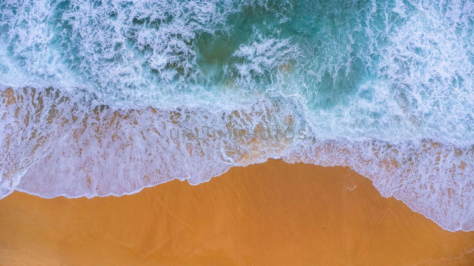 Beautiful sea waves and white sand beach in the tropical island. Soft waves of blue ocean on sandy beach background from top view from drones. Concept of relaxation and travel on vacation. by TEERASAK