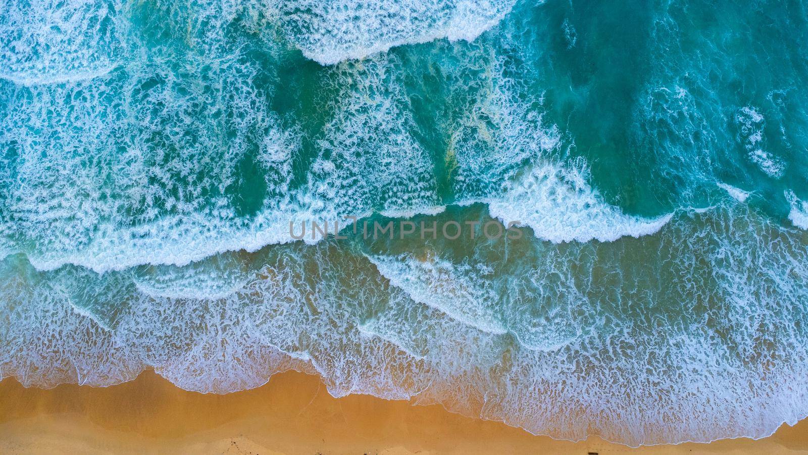 Beautiful sea waves and white sand beach in the tropical island. Soft waves of blue ocean on sandy beach background from top view from drones. Concept of relaxation and travel on vacation.