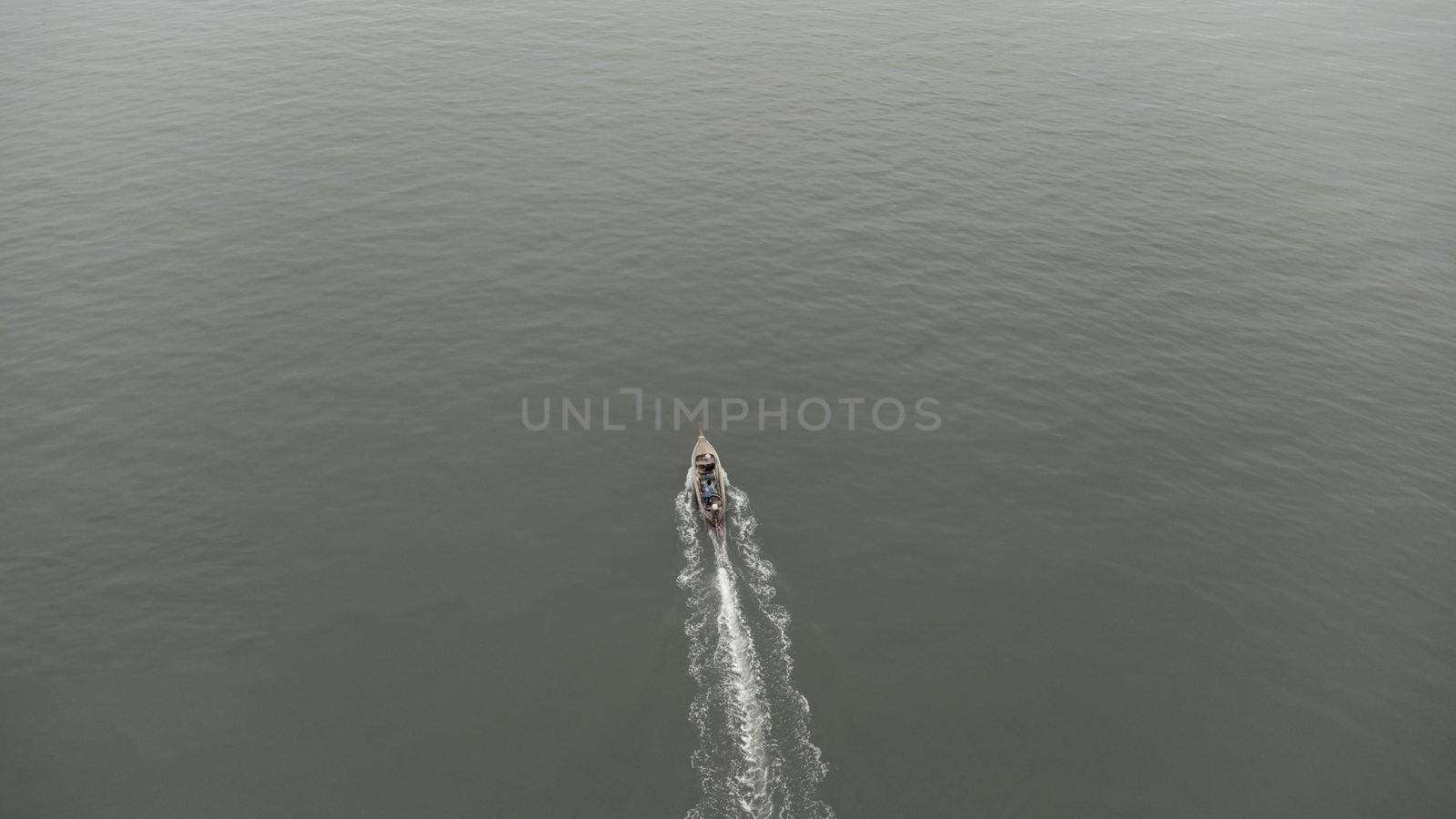 Aerial view from a drone of Thai traditional longtail fishing boats sailing in the sea. Top view of a fast moving fishing boat in the ocean. by TEERASAK