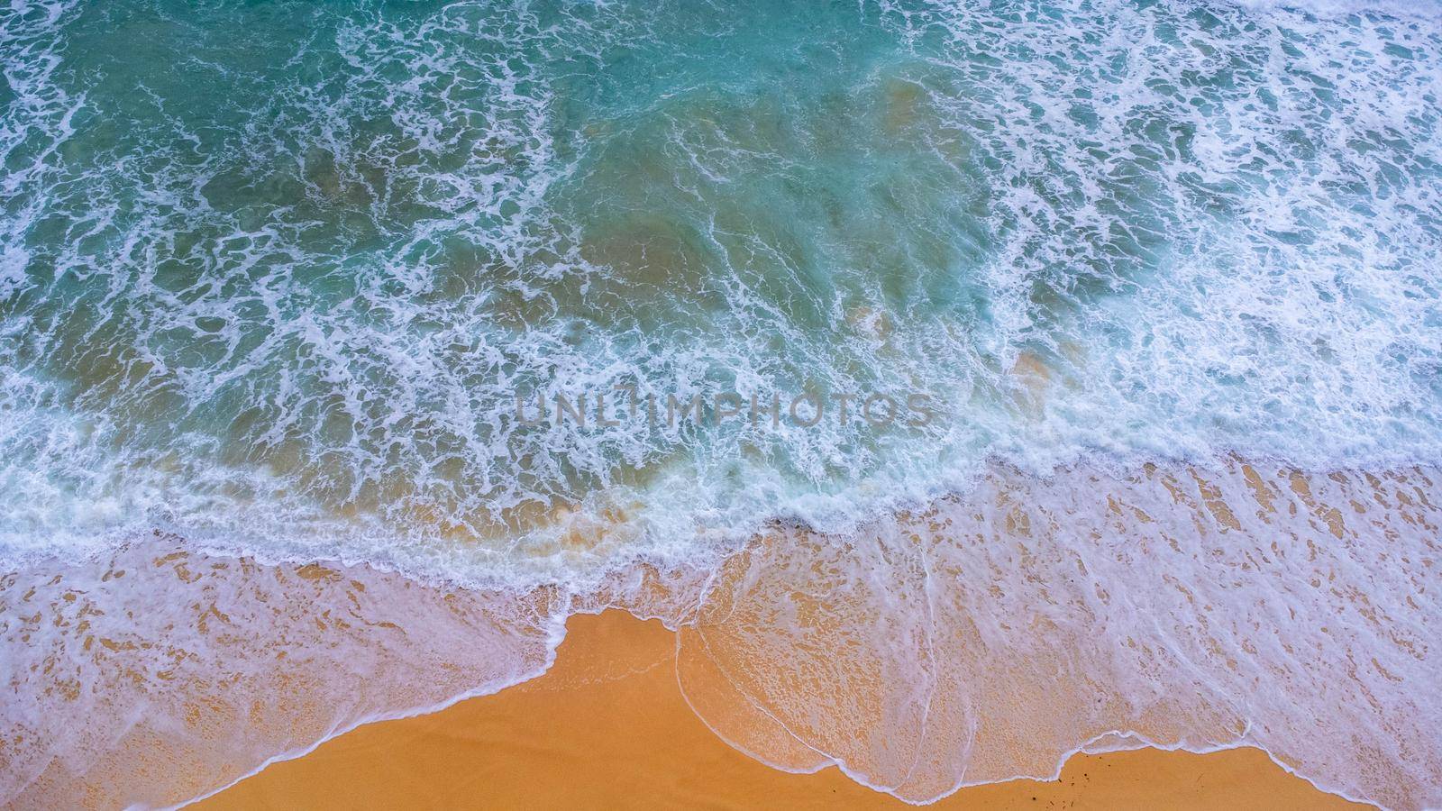 Beautiful sea waves and white sand beach in the tropical island. Soft waves of blue ocean on sandy beach background from top view from drones. Concept of relaxation and travel on vacation. by TEERASAK