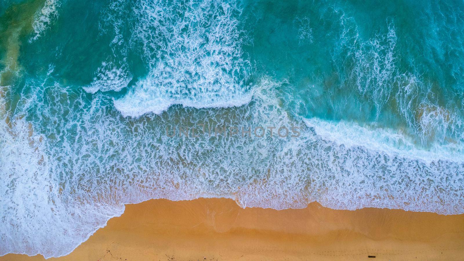 Beautiful sea waves and white sand beach in the tropical island. Soft waves of blue ocean on sandy beach background from top view from drones. Concept of relaxation and travel on vacation. by TEERASAK