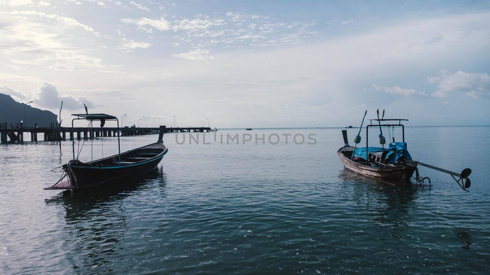 Beautiful scenery of fishing boats at the shore at low tide. A lot of Thai traditional longtail fishing boats in the tropical sea. Pier of the villagers on the southern island of Thailand. by TEERASAK
