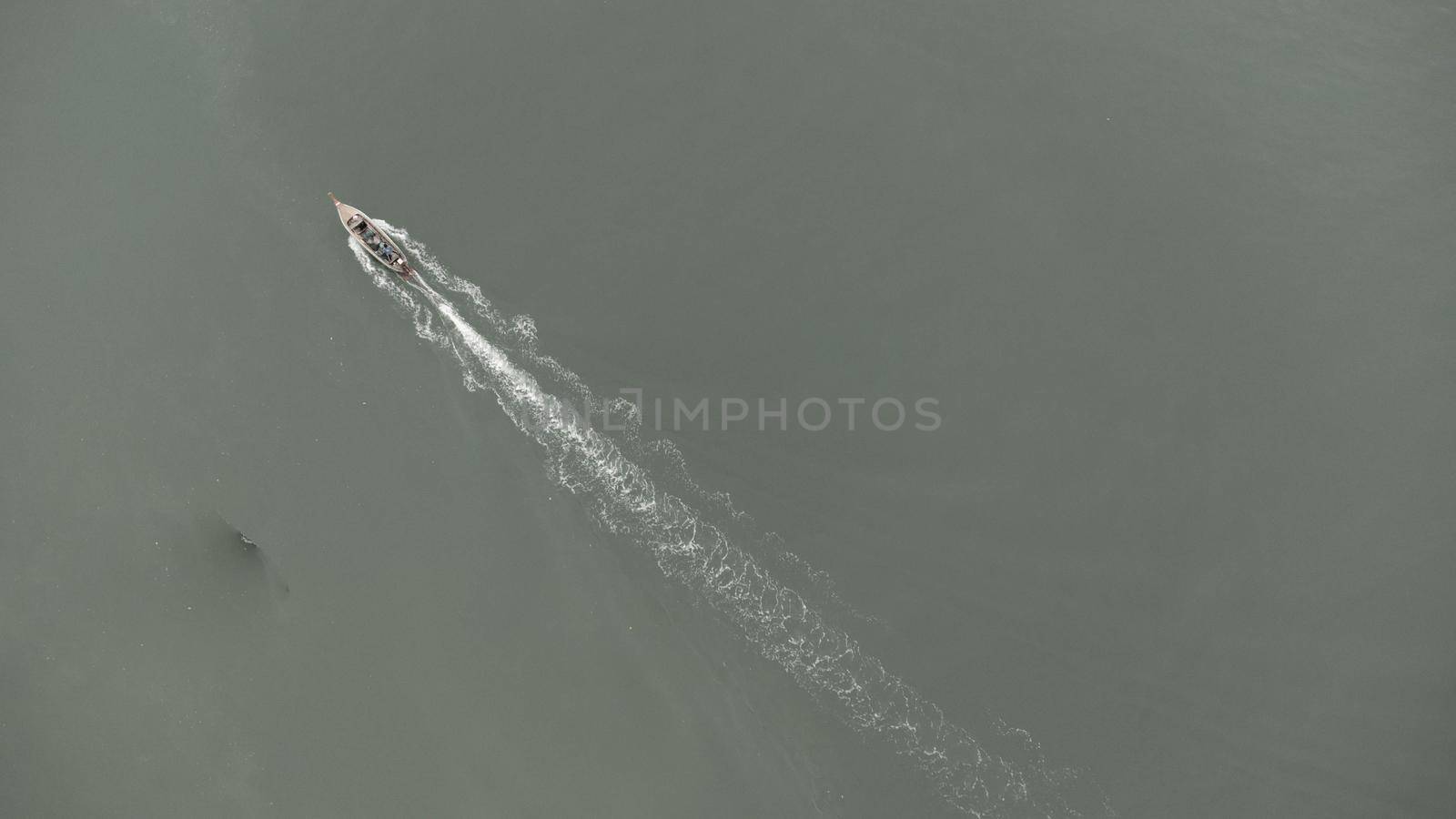 Aerial view from a drone of Thai traditional longtail fishing boats sailing in the sea. Top view of a fast moving fishing boat in the ocean.