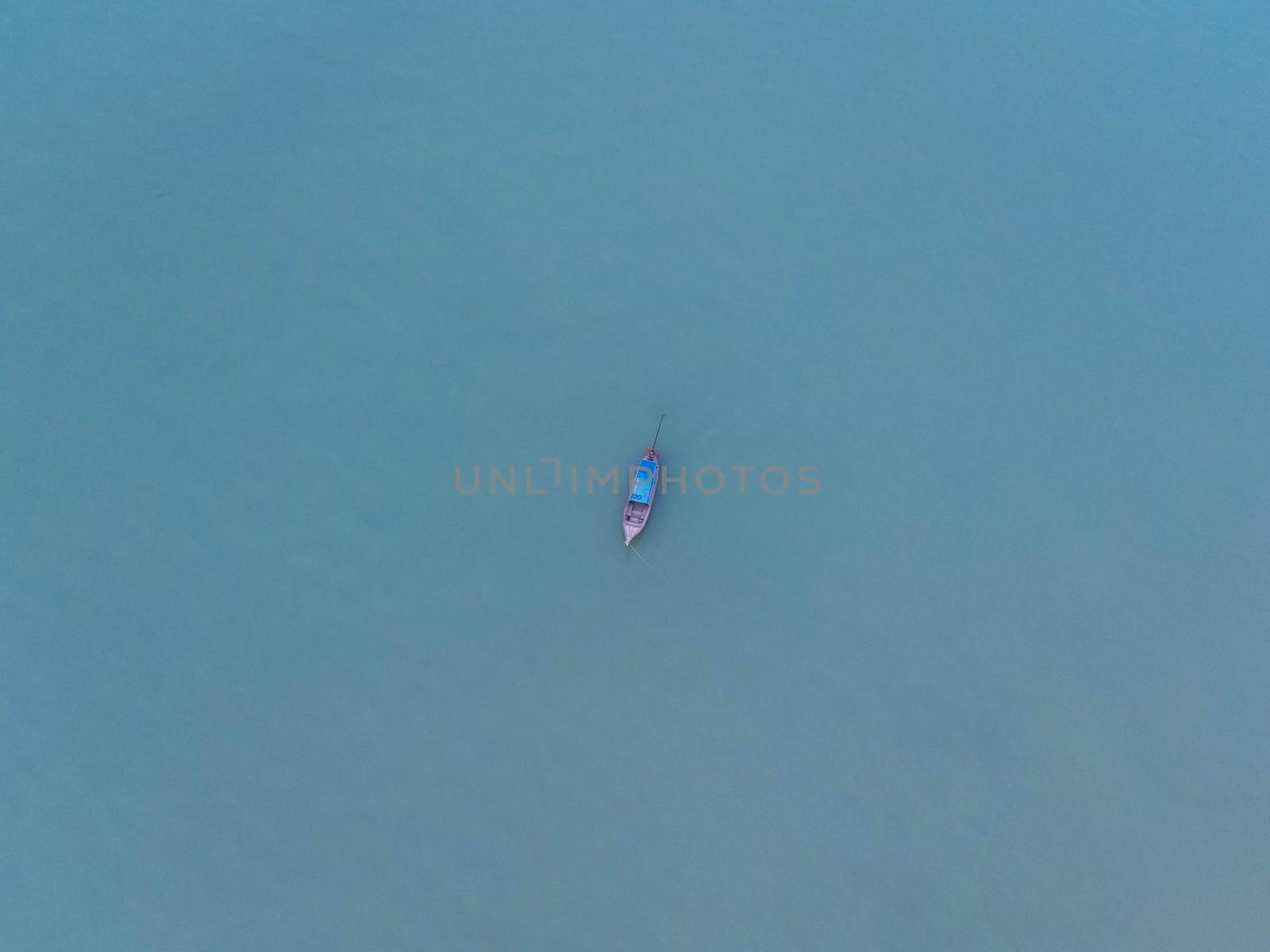 Aerial view from a drone of Thai traditional longtail fishing boats sailing in the sea. Top view of a fishing boat in the ocean. by TEERASAK