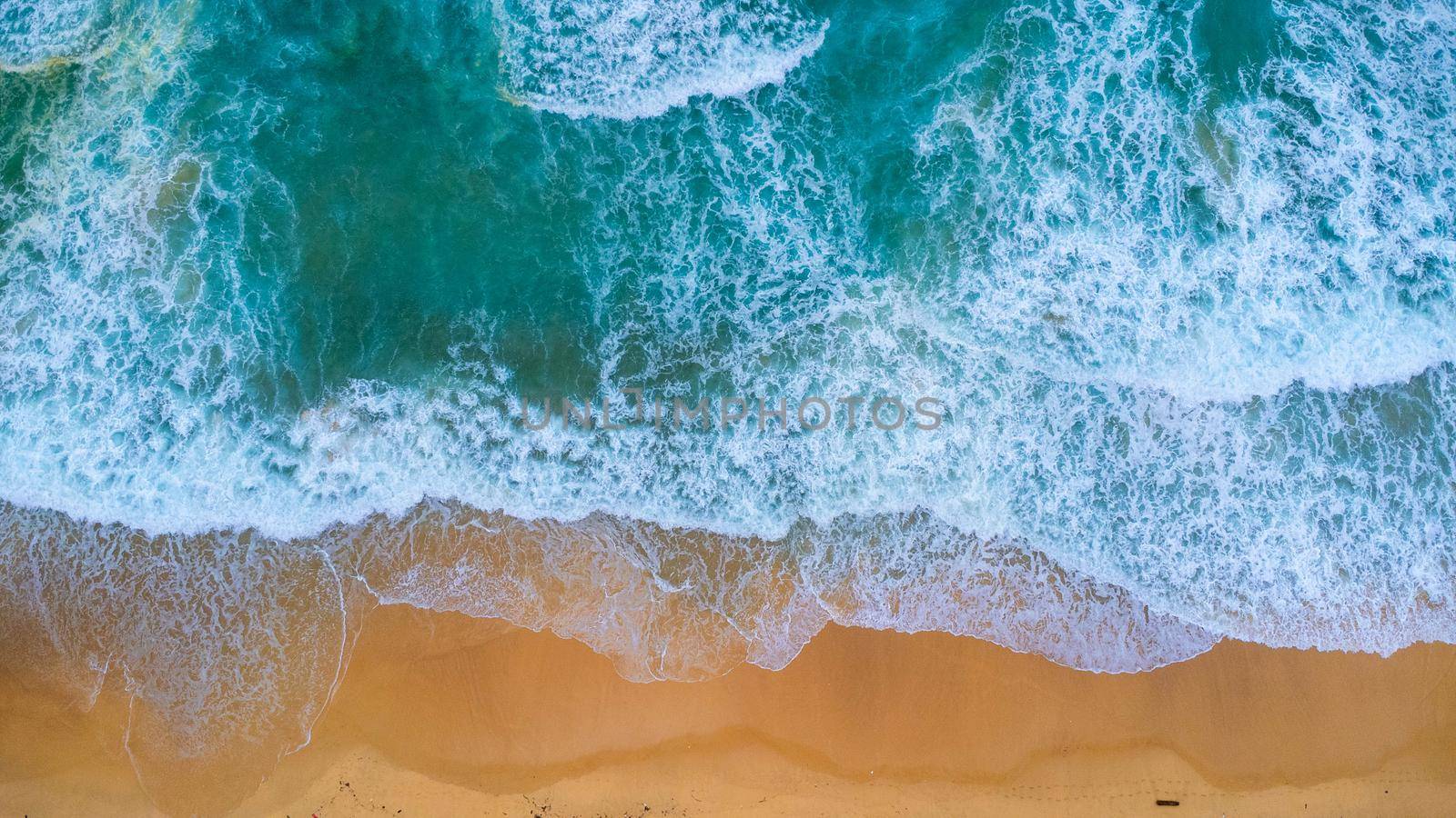 Beautiful sea waves and white sand beach in the tropical island. Soft waves of blue ocean on sandy beach background from top view from drones. Concept of relaxation and travel on vacation. by TEERASAK
