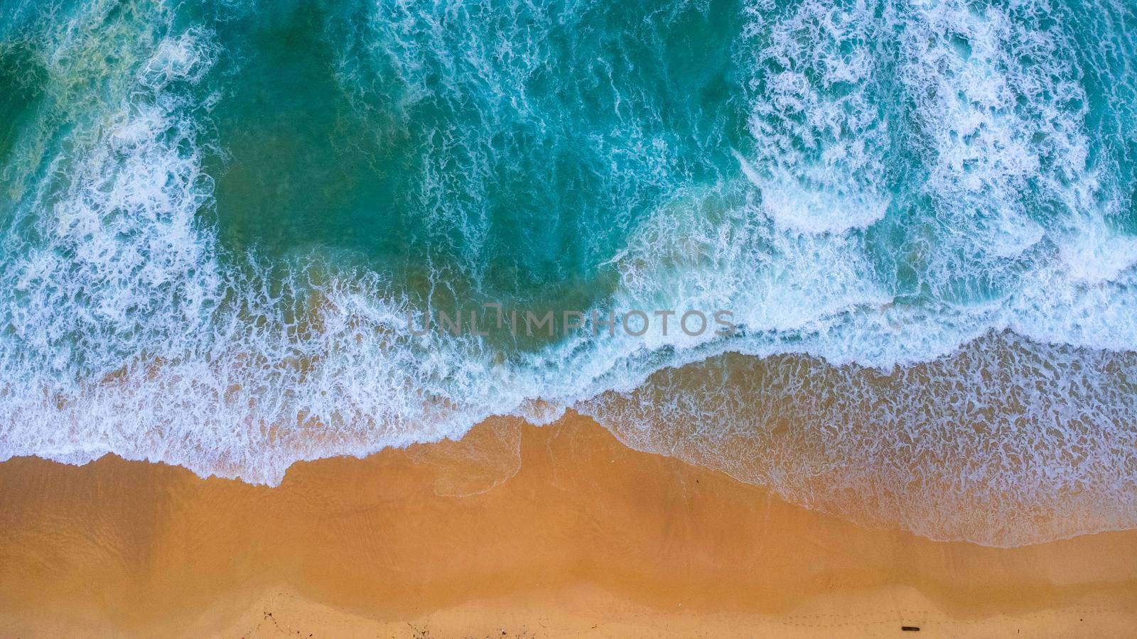 Beautiful sea waves and white sand beach in the tropical island. Soft waves of blue ocean on sandy beach background from top view from drones. Concept of relaxation and travel on vacation. by TEERASAK