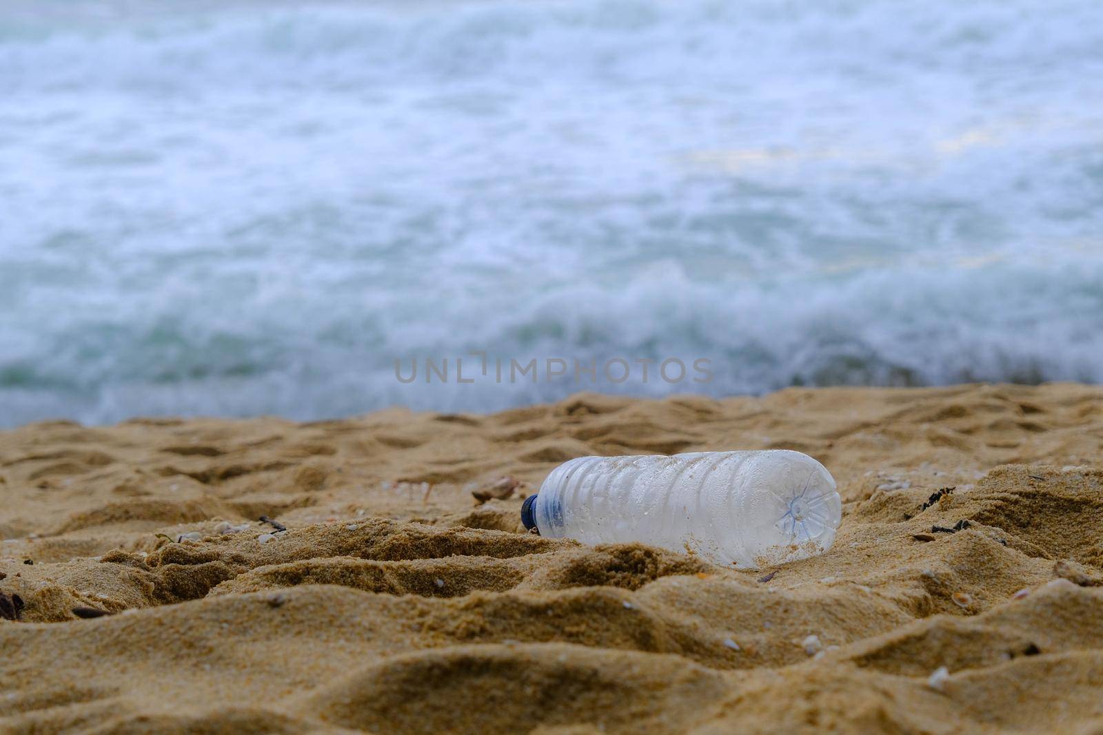 Plastic water bottle on the beach. Concept of plastic pollution and environmental problems by TEERASAK