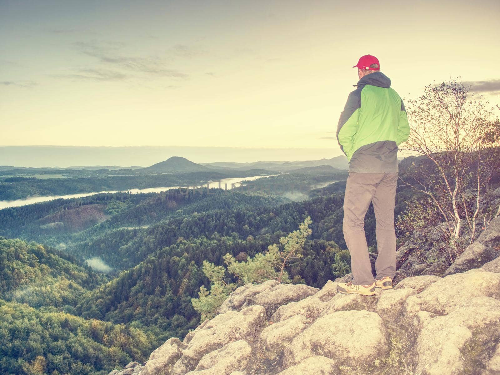 Sharp cliff edge with man watching over misty land by rdonar2