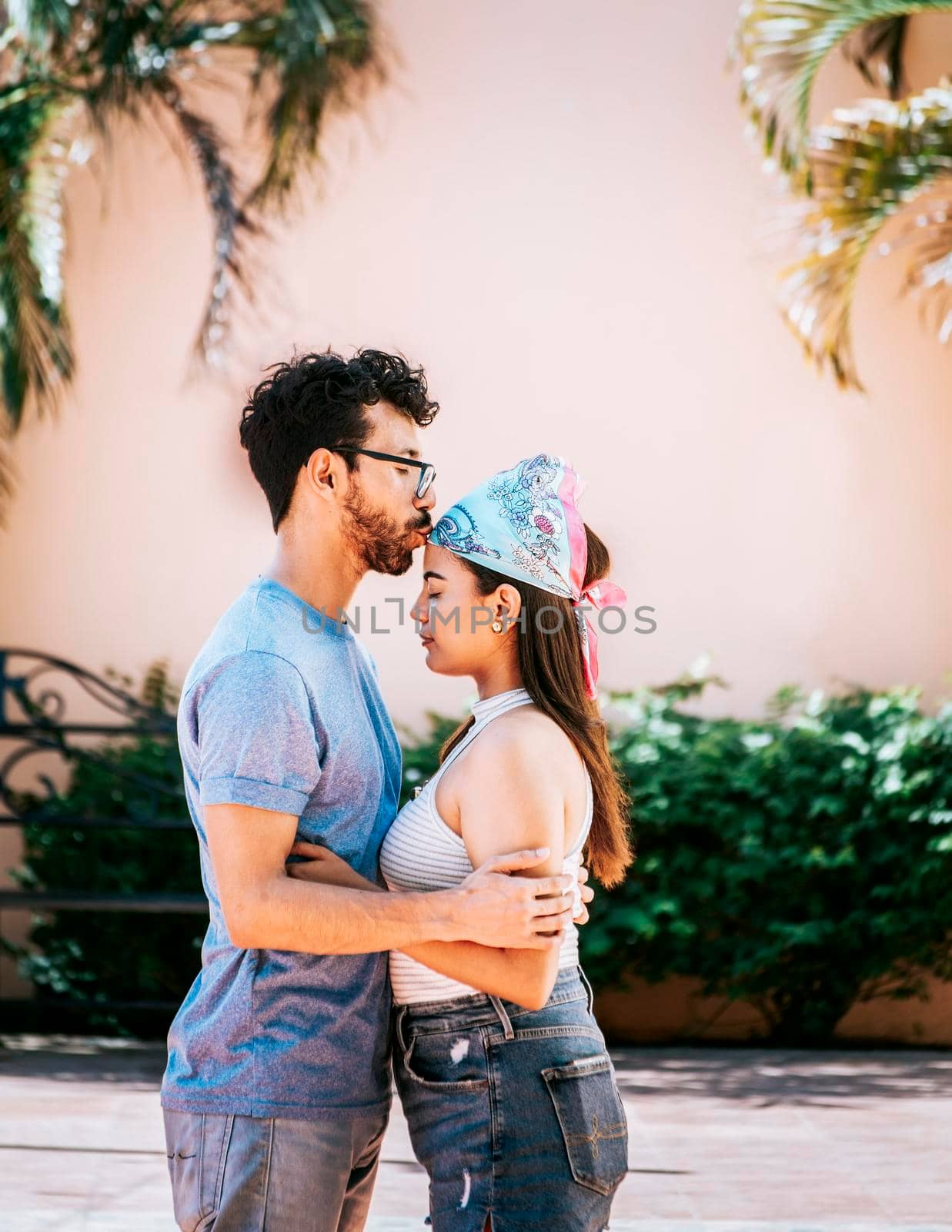 Boyfriend tenderly kissing his girlfriend forehead. Man kissing his girlfriend forehead outside. Cute couple embracing the boyfriend kisses the girl forehead. Portrait of beautiful couple in love by isaiphoto