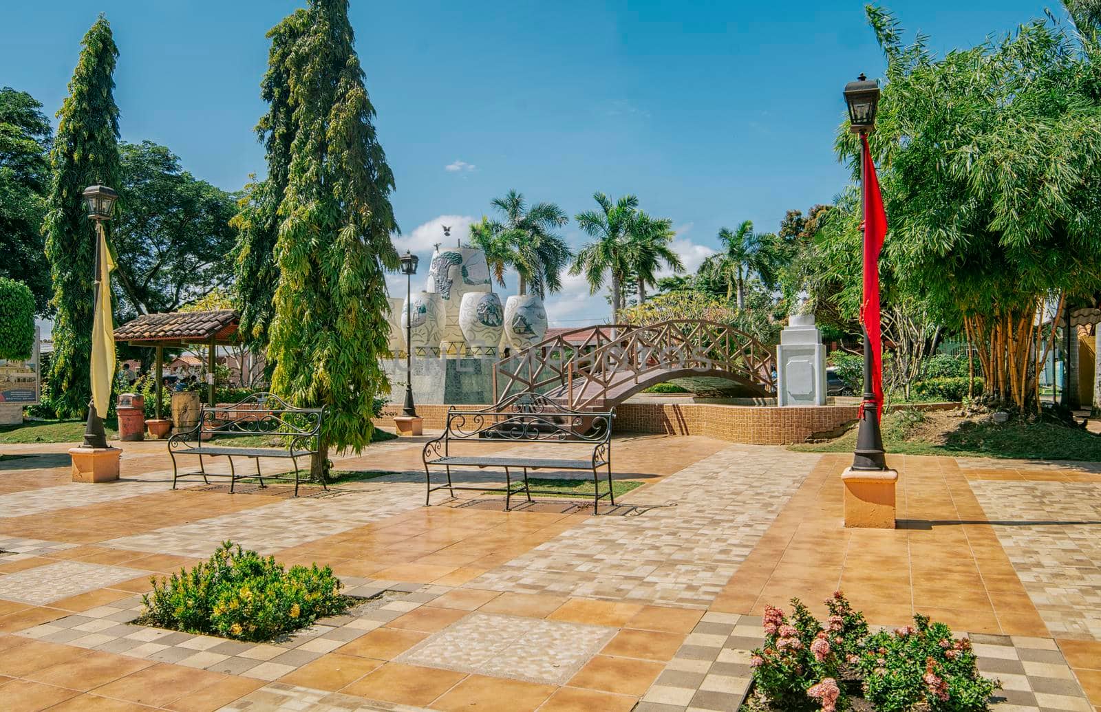 A nice and relaxed park with a wooden bridge over a water fountain, Traditional park of Nagarote, Nicaragua. View of a calm park with a small wooden bridge on a sunny day. Nagarote central park