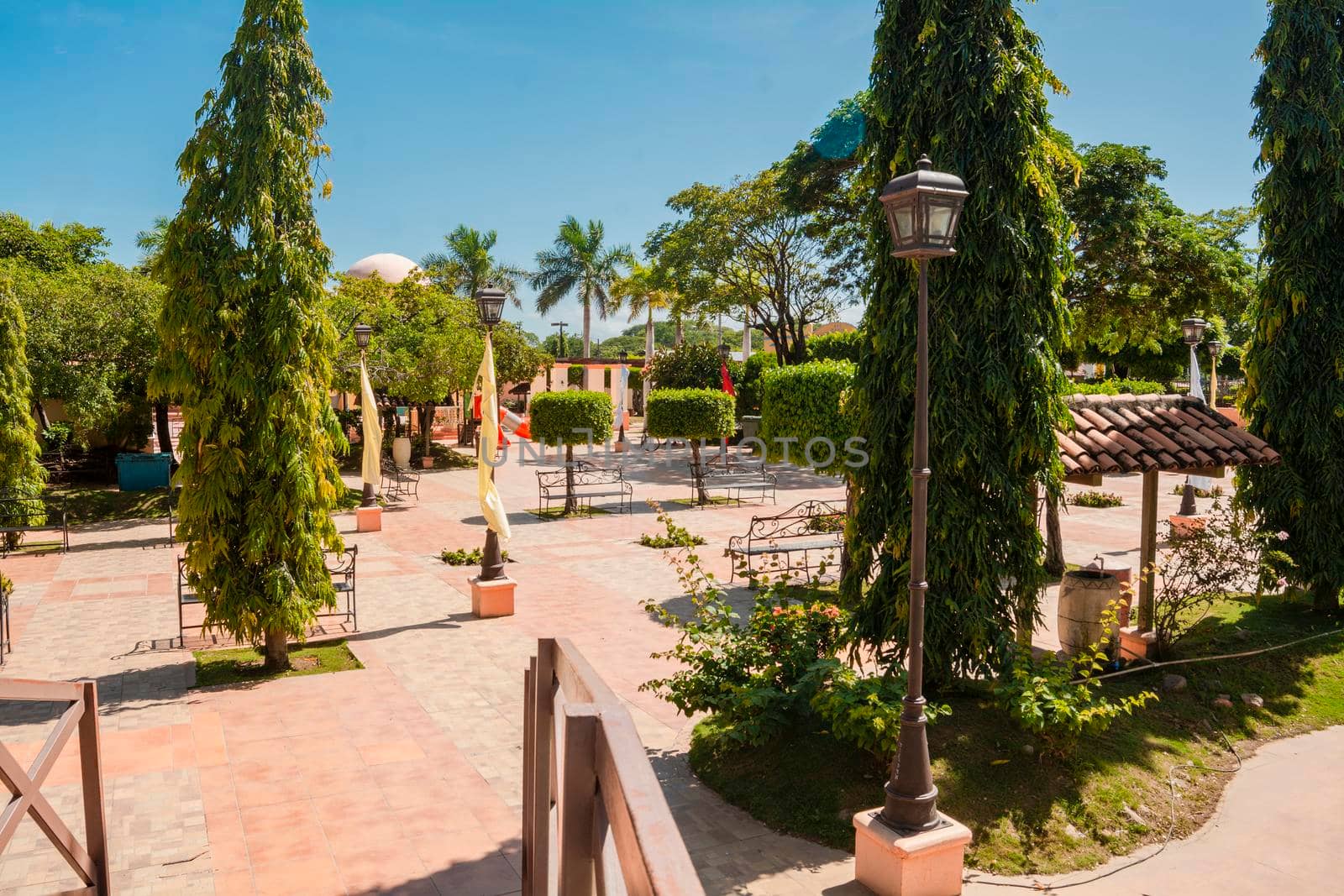 View of a nice urban park surrounded by green trees on a sunny day, View of a small quiet urban park with small green trees. Central Park of Nagarote, Nicaragua