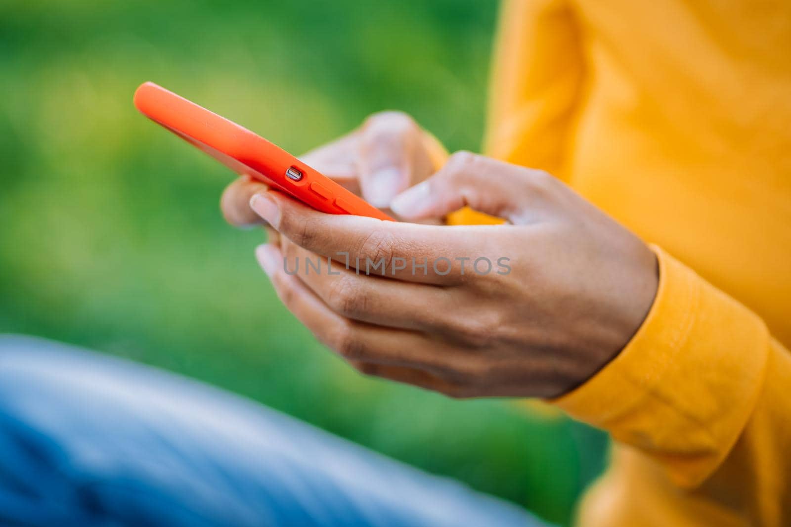 African woman using mobile phone over green background. Close up beautiful hands holding smartphone. Black female using technology