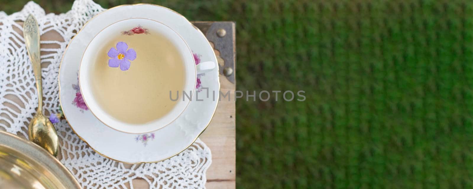 porcelain cup with tea and flower floats in tea, vintage still life, top view, bunner ,High quality photo