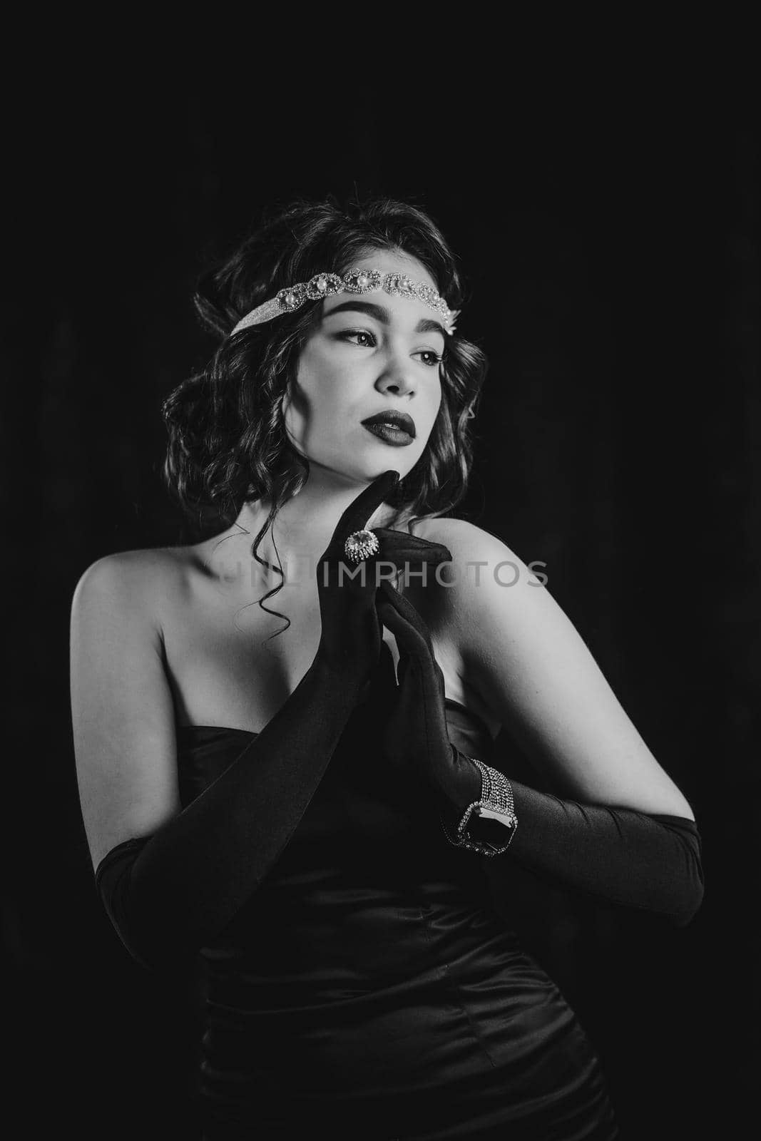 Woman dressed in twenties last century era with feathers boa on dark background. Retro, party, fashion concept. Black and white film effect. High quality photo