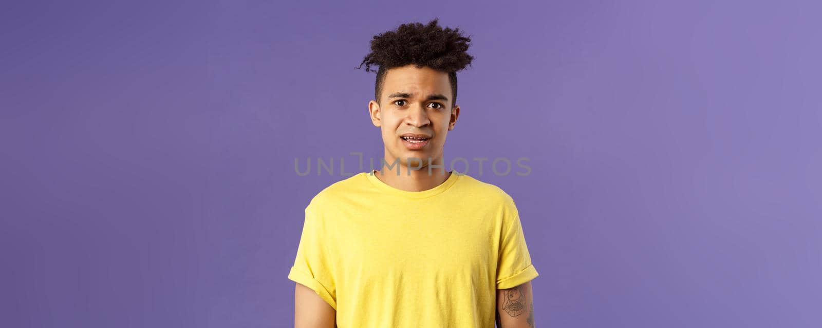 Waist-up portrait of young concerned hispanic man with worried gaze looking at camera, frowning being scared for friend stuck in troublesome situation, want help, stand purple background by Benzoix