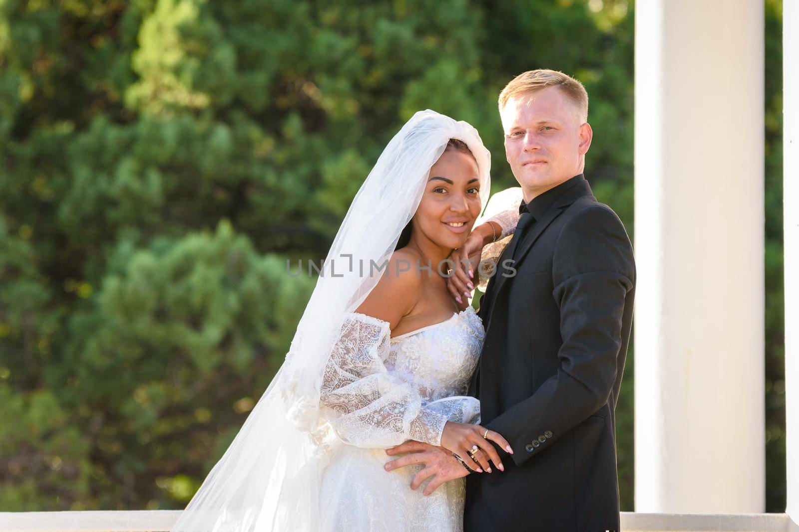 Mixed race newlyweds on a walk hugging and looking into the frame