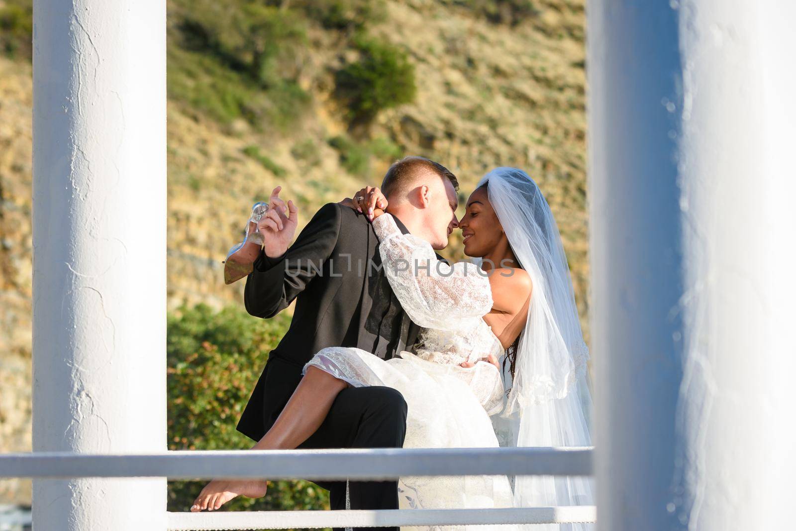 Young beautiful interracial newlyweds kissing in the gazebo