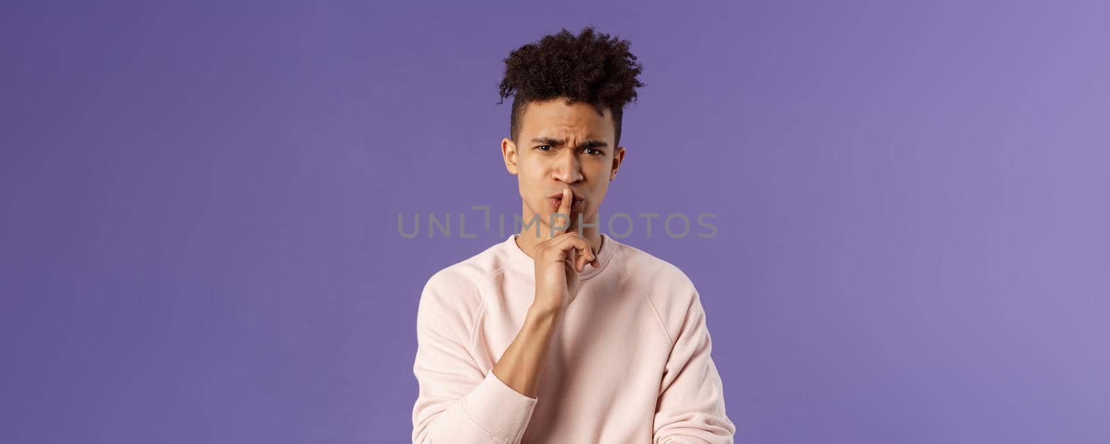 Show some respect. Portrait of angry and annoyed, displeased young hispanic man telling to keep quiet, shushing at someone being too loud, hold index finger over mouth frowning, scolding person.