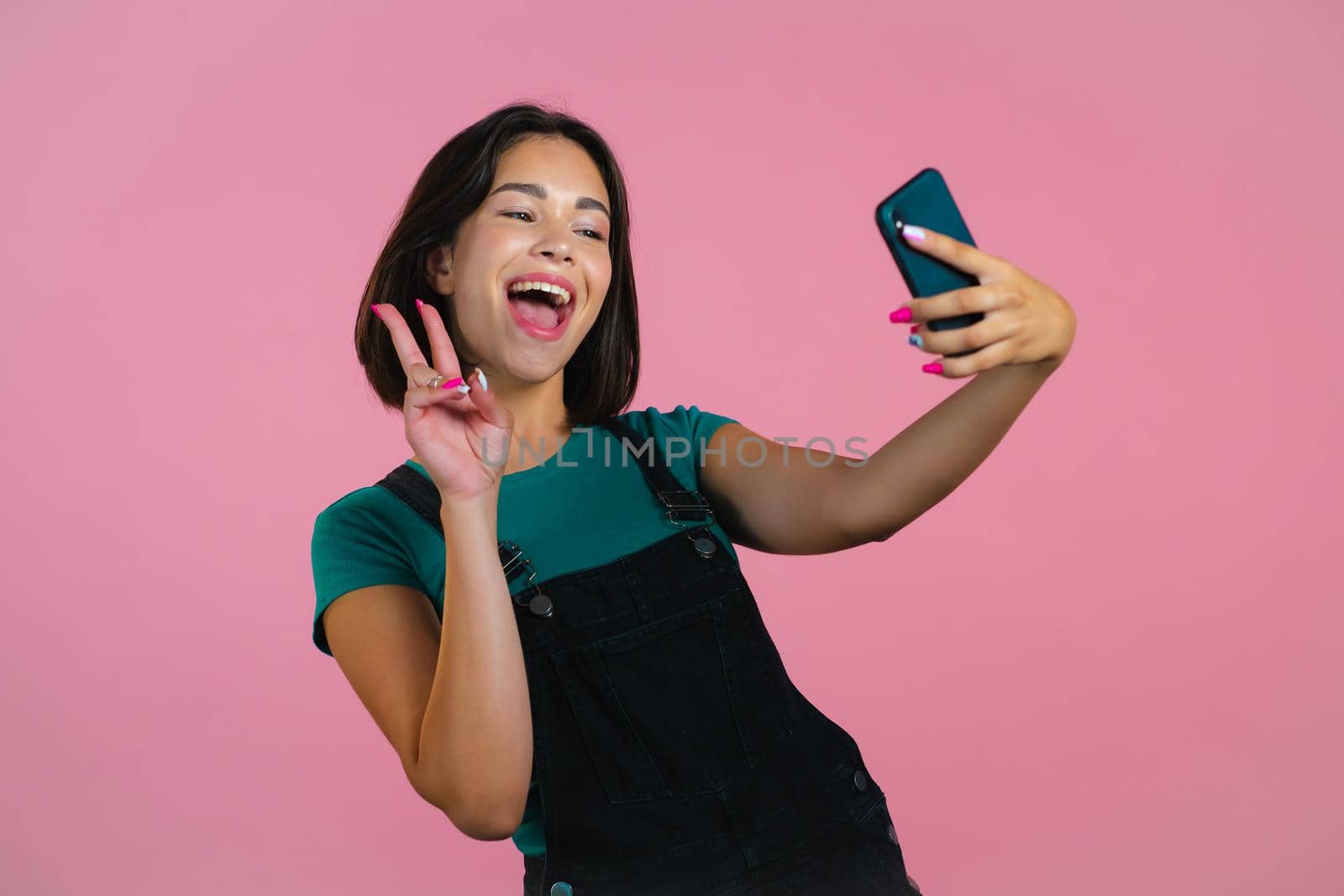 Smiling happy woman making selfie on smartphone over pink background. Technology, mobile device, social networks concept by kristina_kokhanova