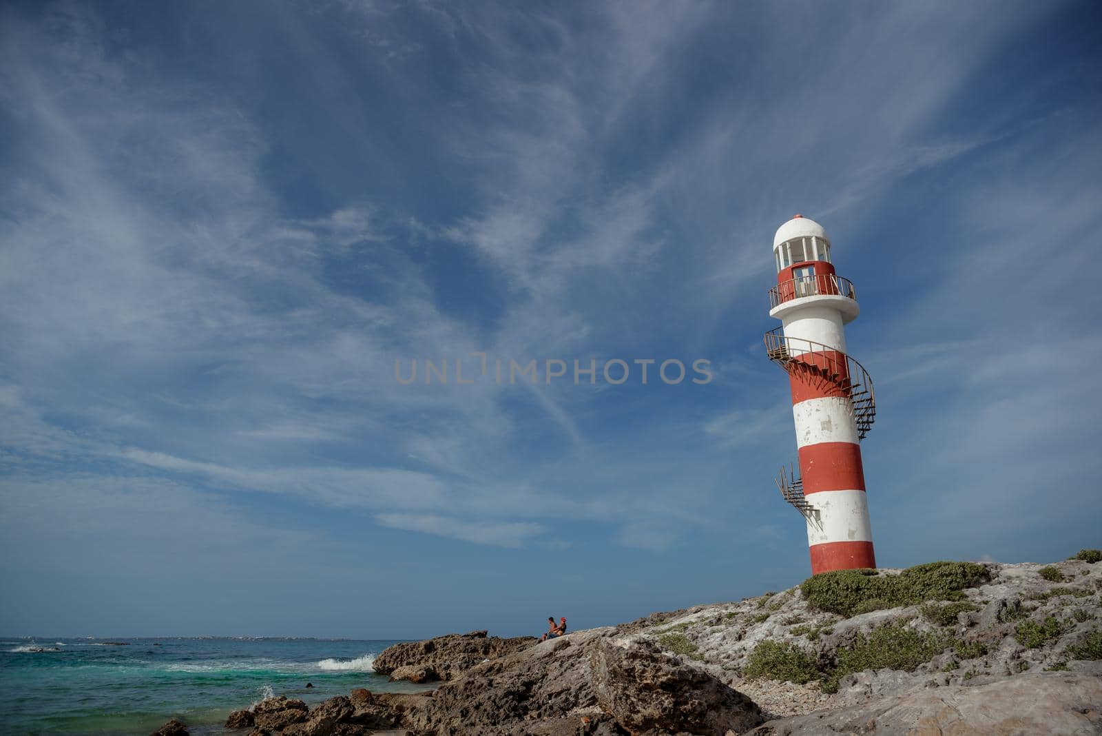 Lighthouse on a rocky shore in Cancun. Clear sky and blue sea.